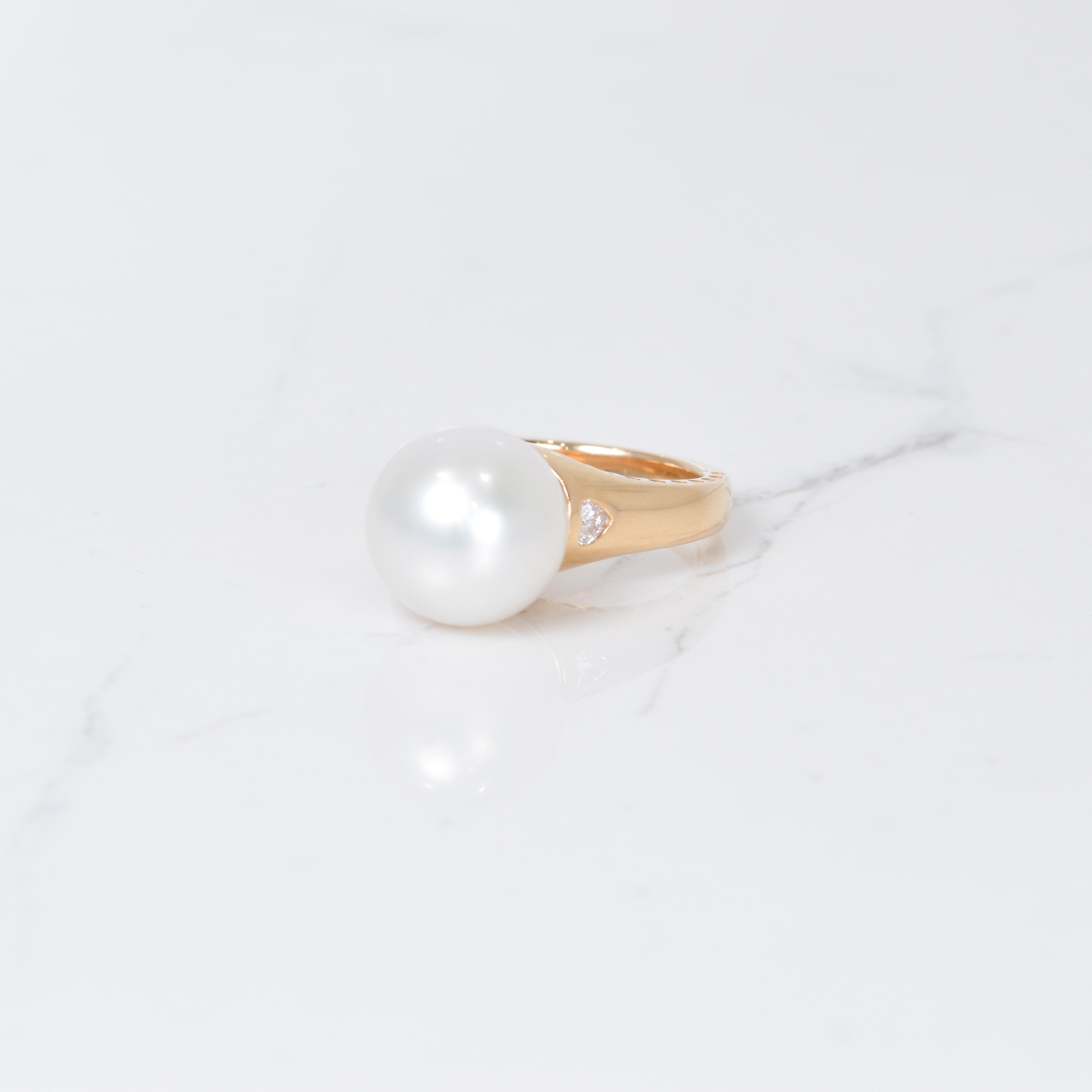 Les perles et les diamants vont bien ensemble ! Cette magnifique bague est ornée en son centre d'une magnifique perle de mer du Sud de 12 mm de diamètre. Cette perle scintillante est rehaussée de deux magnifiques diamants en forme de cœur totalisant