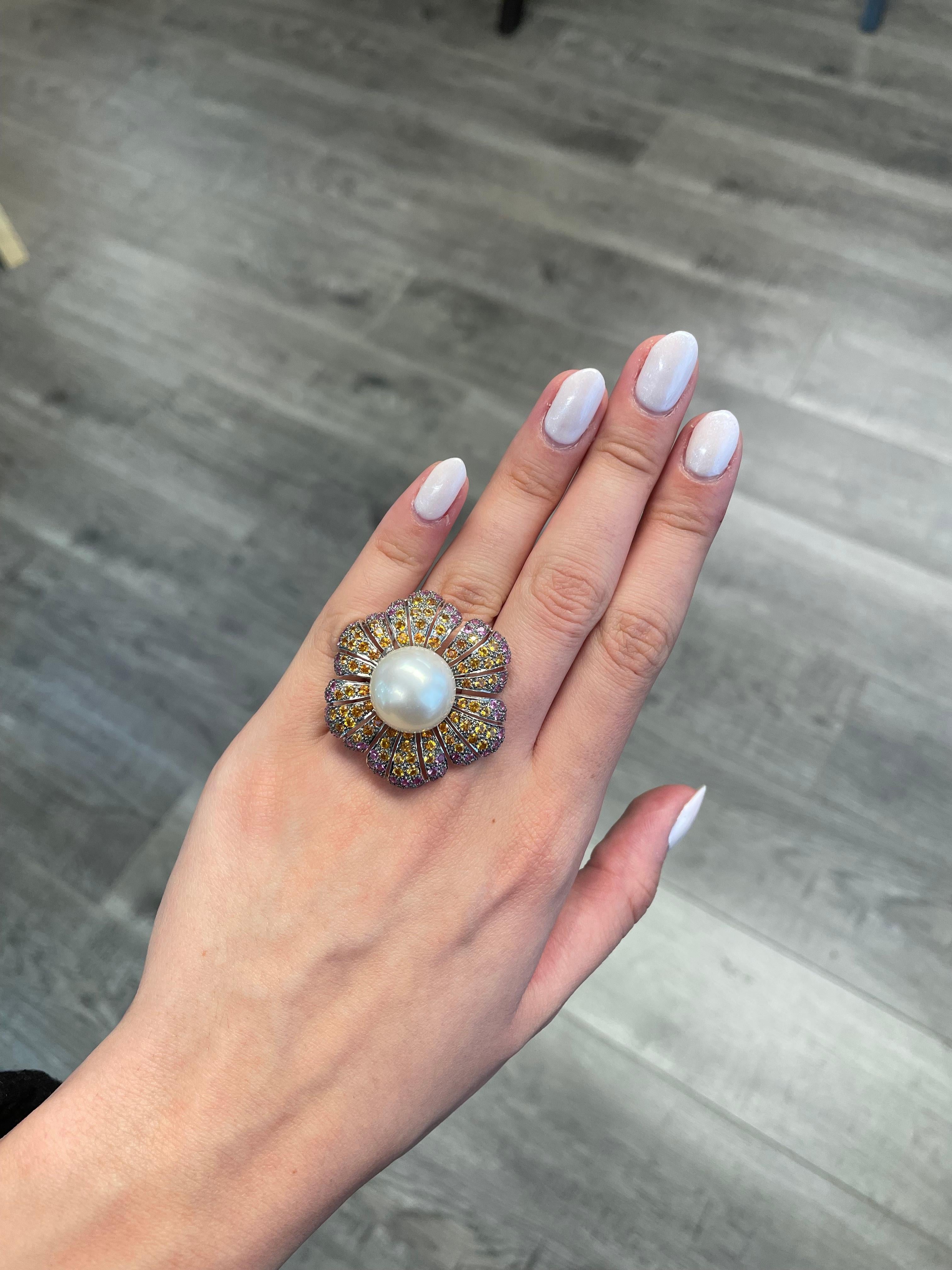 Exquisite and unique multi gemstone floral ring. 
Center South Sea pearl surrounded by 3.55ct of pink sapphires heat and 3.20ct of yellow & orange sapphires. 6.75ct total gemstone weight set in 18-karat white gold with black rhodium. 
Accommodated