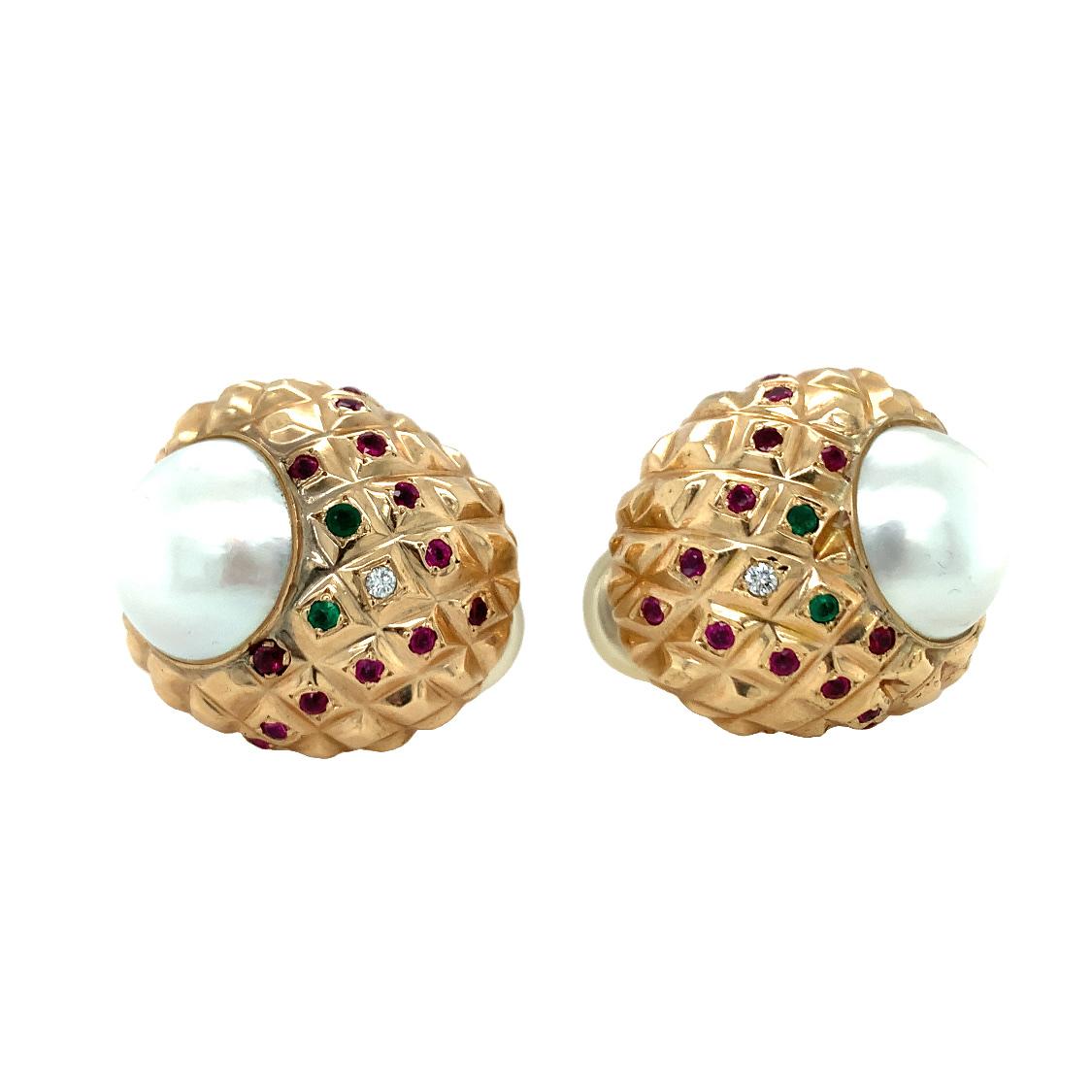One pair of pearl and multi-gem 18K yellow gold earrings featuring two white mabe pearls measuring 15 millimeters in diameter with rosey overtones. The chunky, close to the ear hoop earrings are further accented by 26 round rubies weighing 1.10 ct.,