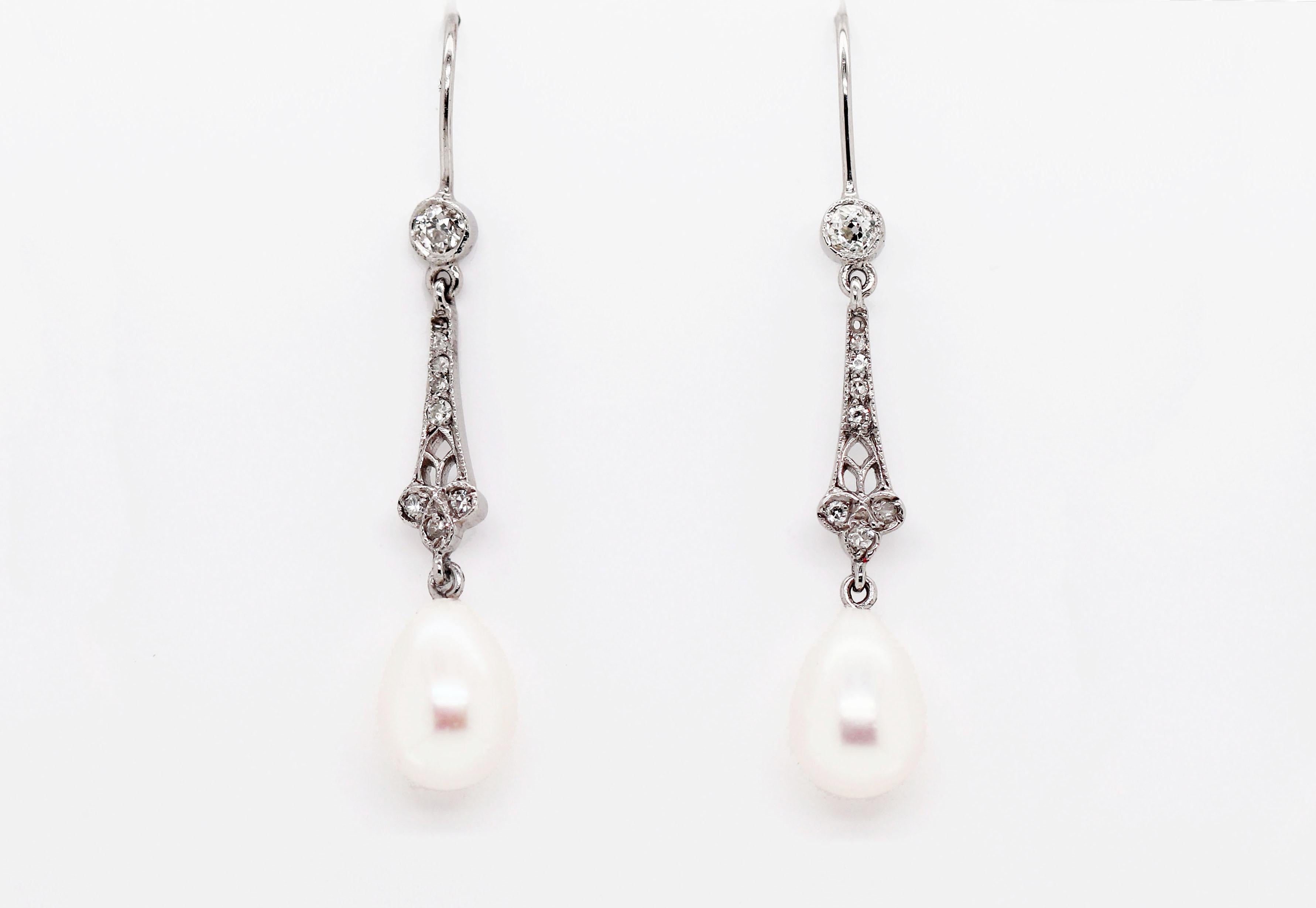 Beautifully delicate pair of drop earrings featuring teardrop cultured pearls hanging from an intricate open work design set with eight old cut diamonds in milgrain settings and finished with a larger diamond at the top in a rub over milgrain