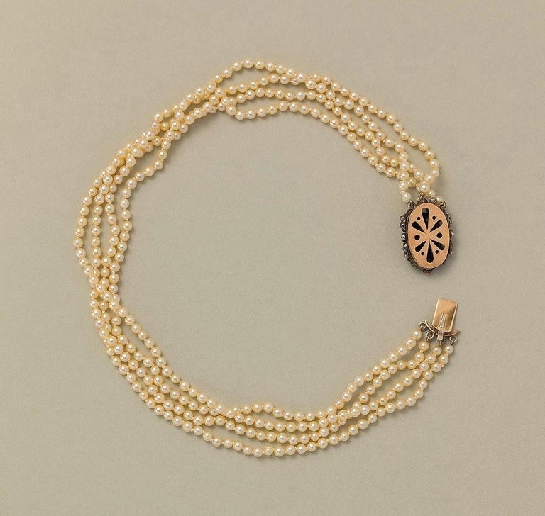 A necklace with 4 rows of cultured pearls and a 14 carat gold lock made of an antique silver and rose cut diamond element 

weight: 31.47 grams 
length: 37.5 cm 