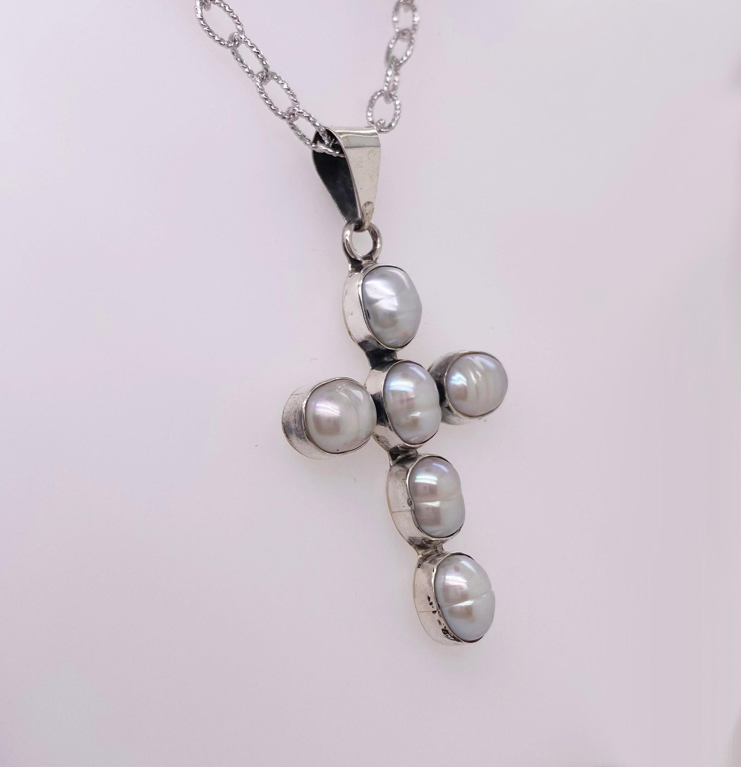 This gorgeous cross necklace was handmade with genuine freshwater pearls. The six pearls are elongated and make a lovely shape for the cross. 
 The back of the cross is solid sterling silver and it hangs from a handmade cable chain.  The chain is