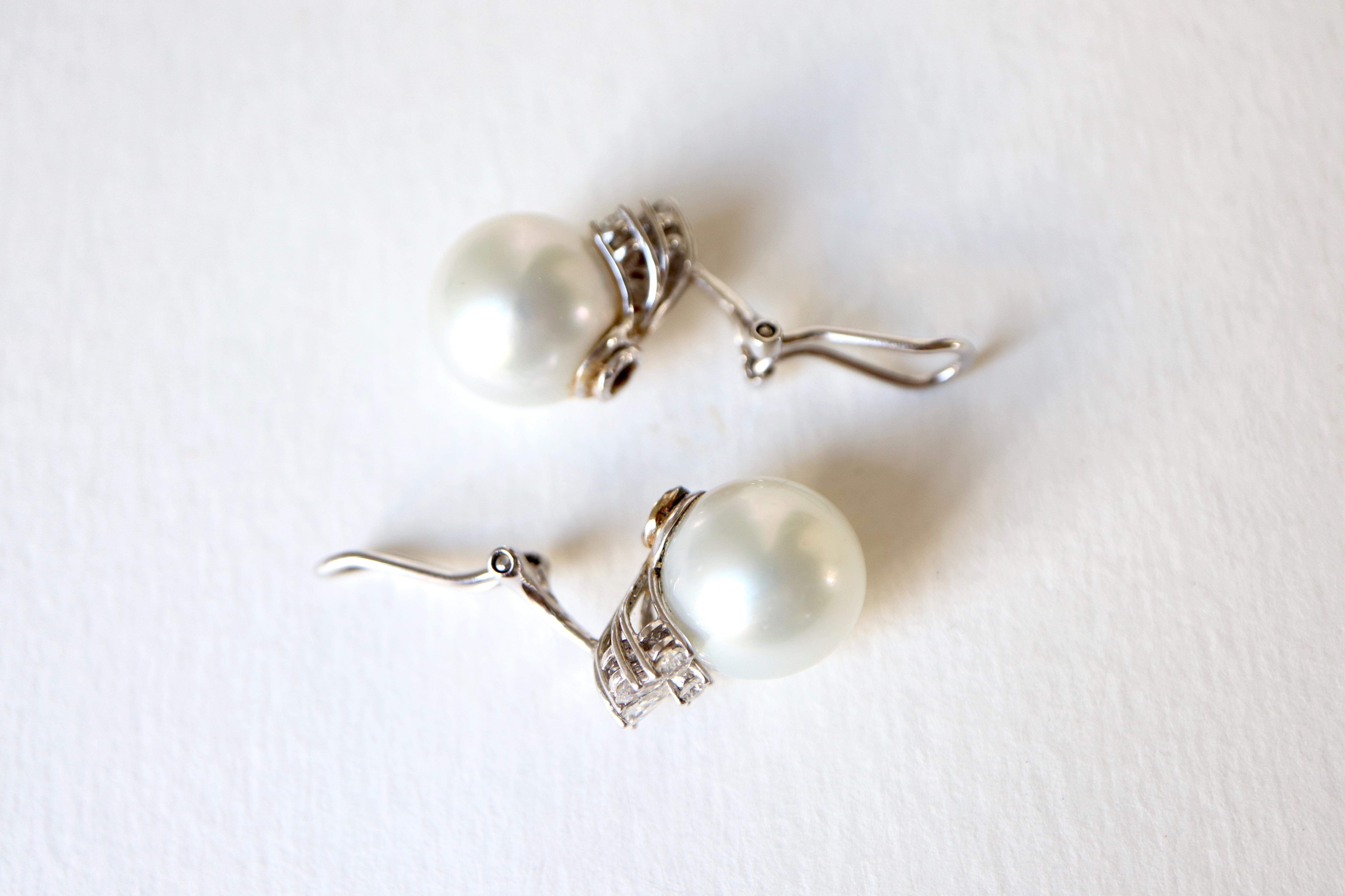 18 kt white gold pearl and diamond earrings. 
They each hold a large cultured pearl 13.5 mm in diameter decorated below with diamonds forming a half-daisy pattern composed of a round diamond in its center and 5 pear-shaped diamonds.
Total weight of