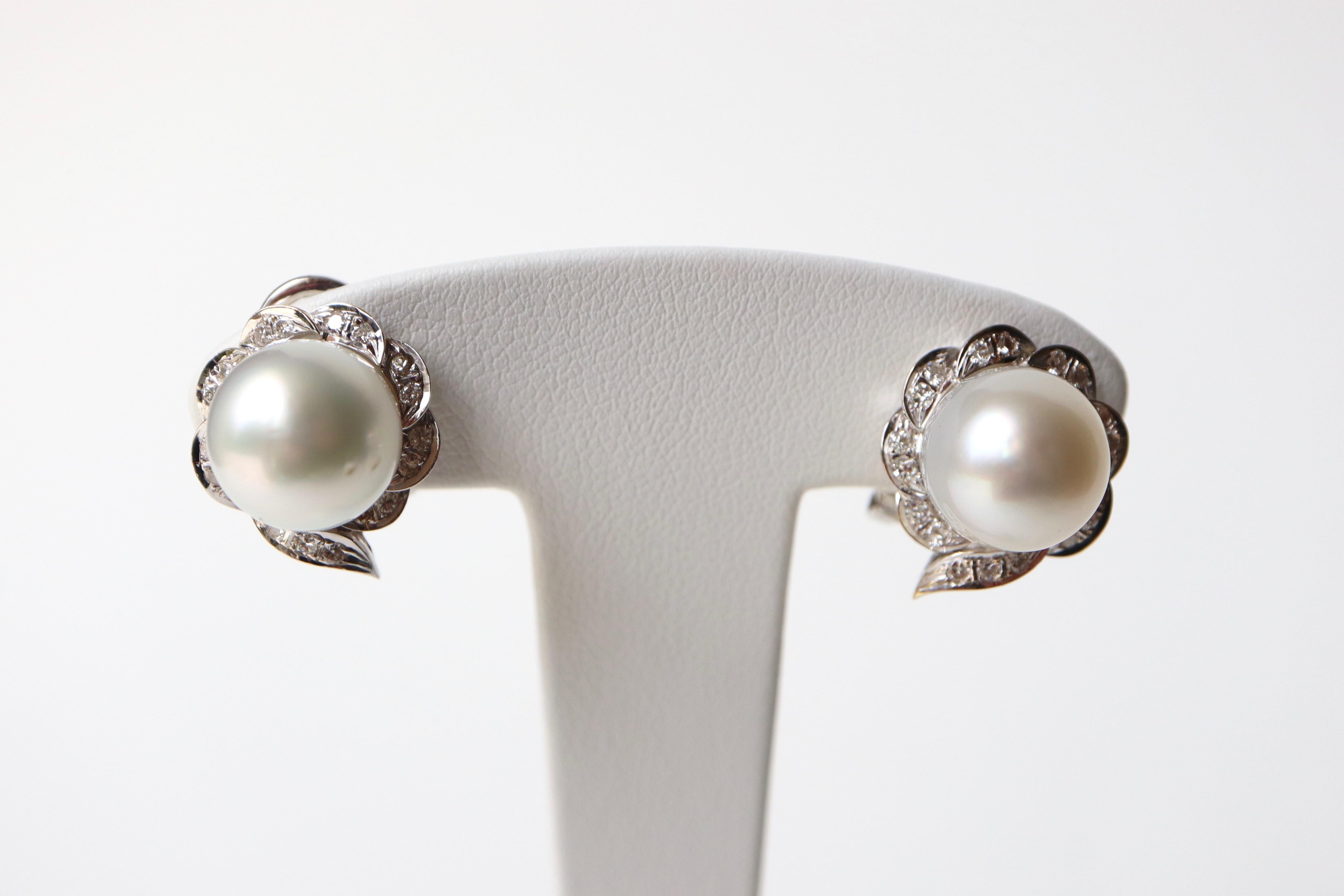 Vintage earrings, 11 mm cultured pearls, 18 carat white gold and diamonds circa 1960
Ear clips for non-pierced ears with a flower motif, the heart of which is an 11 mm South Sea cultured pearl surrounded by 18-carat white gold petals set with