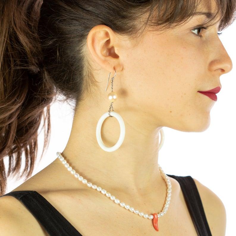 An elegant and light weighted freshwater pearl earrings, necklace and bracelet with a unique design with a central pendant in red coral. Immerse yourself in the beauty of this uniquely designed set with natural stones full of life and color. A