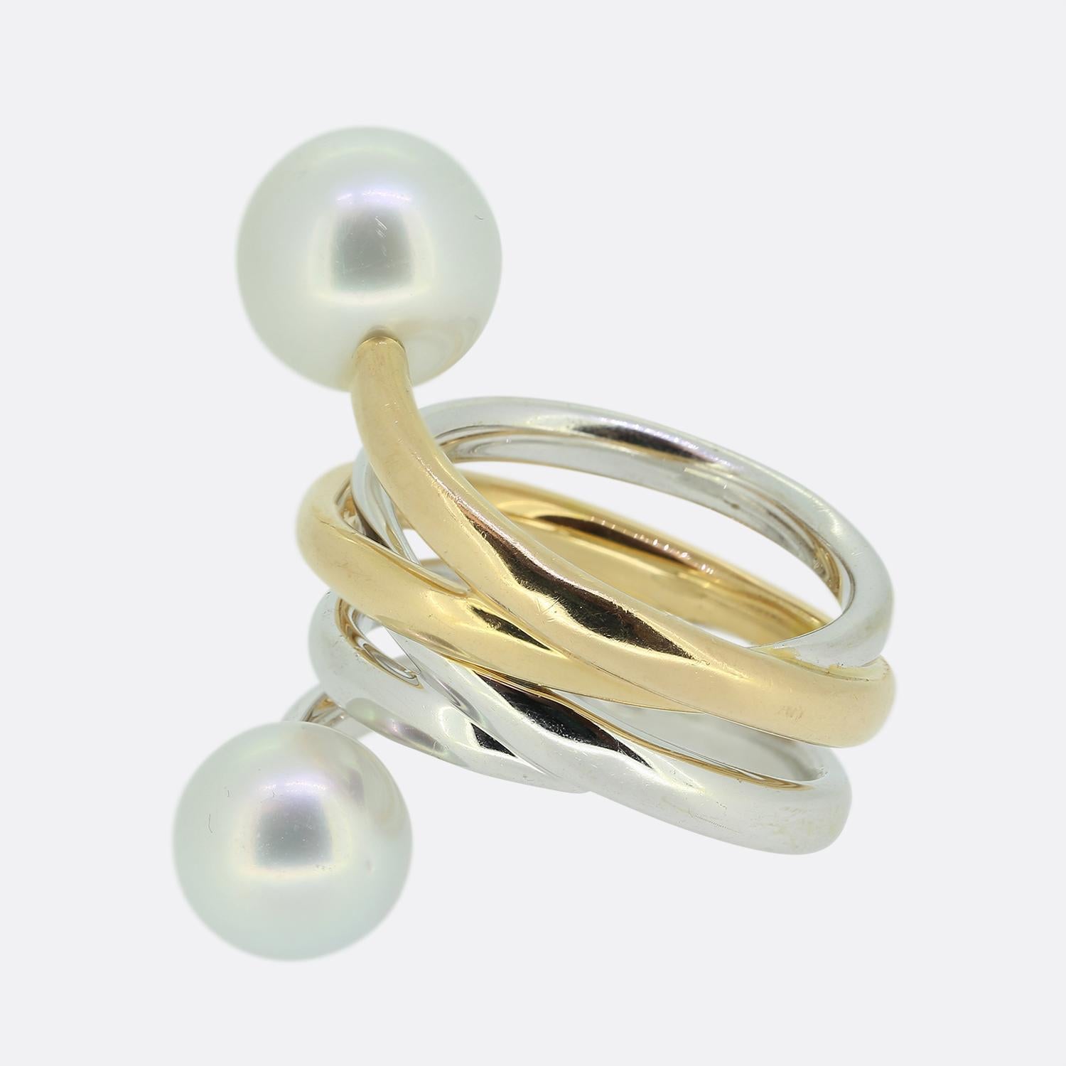 Hier haben wir einen einzigartig gestylten Perlenring aus 18 Karat Gold. Dieses Schmuckstück besticht durch zwei abgerundete Zuchtperlen am Ende der sich weit überlappenden Bänder aus Weiß- und Roségold.

Zustand: Gebraucht (Sehr gut)
Gewicht: 19.6