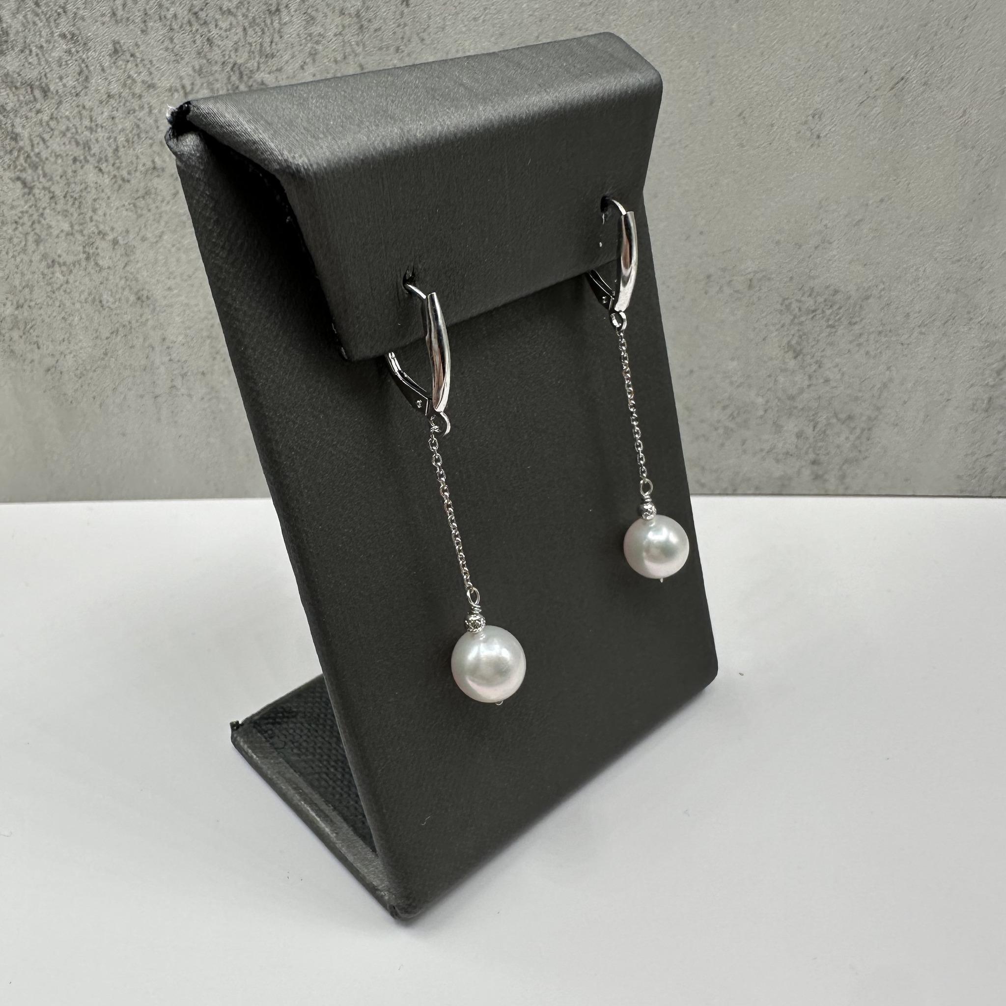 Ces élégantes boucles d'oreilles pendantes en or blanc 14 carats sont ornées de perles d'eau douce rondes d'environ 8,2 à 8,4 mm de diamètre qui rayonnent d'une sophistication intemporelle. Les perles lisses et lumineuses sont suspendues à des dos à