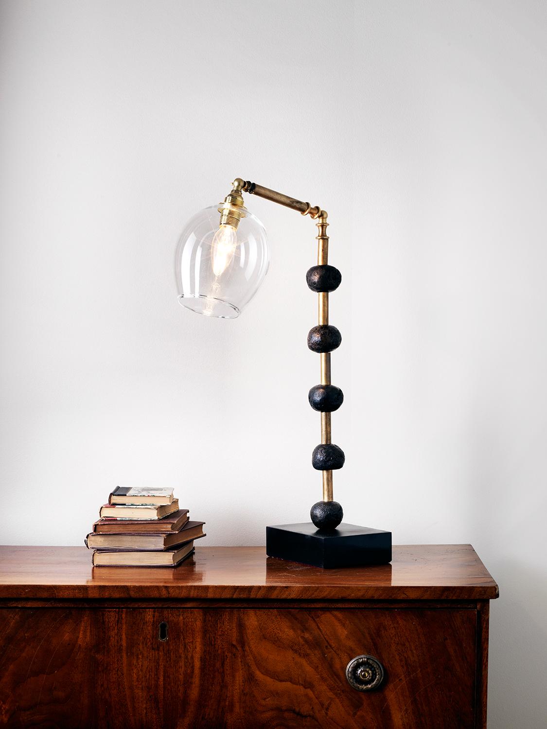 This contemporary Margit Wittig table lamp is mounted on a slate base and features multiple bronze resin handcrafted spheres. Each element is hand patinated to increase tonal contrast and enhance the surface texture.

This statement piece which will