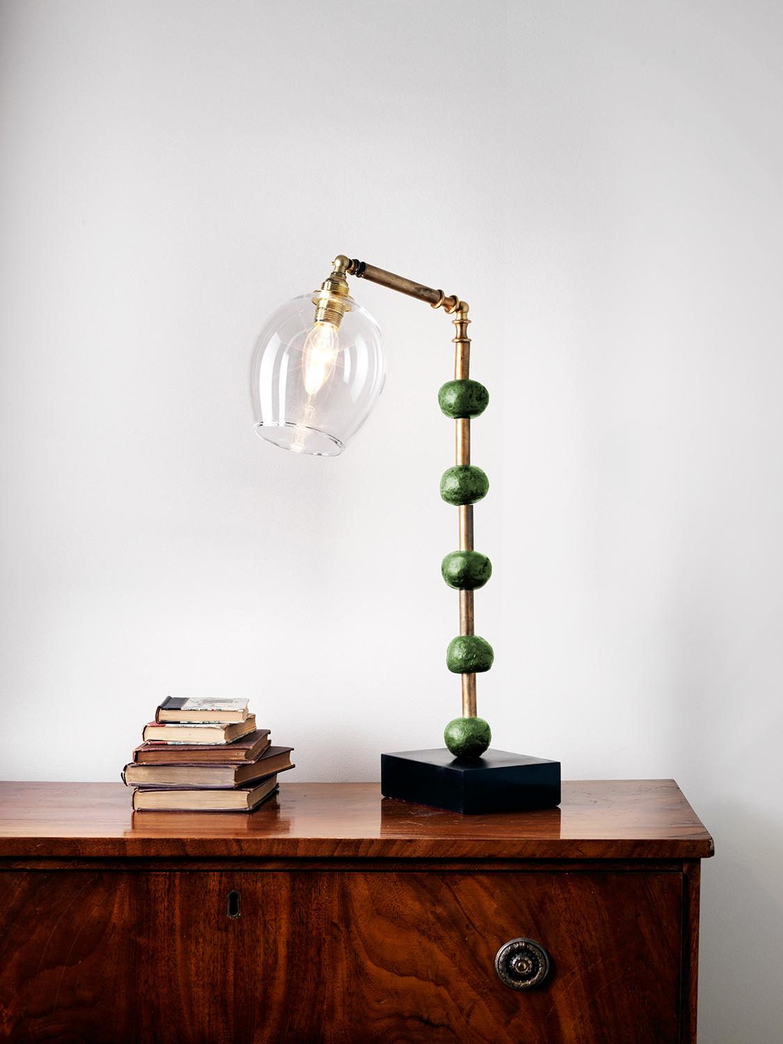 This contemporary Margit Wittig table lamp is mounted on a slate base and features multiple green resin handcrafted spheres. Each element is hand patinated to increase tonal contrast and enhance the surface texture.

This statement piece which will