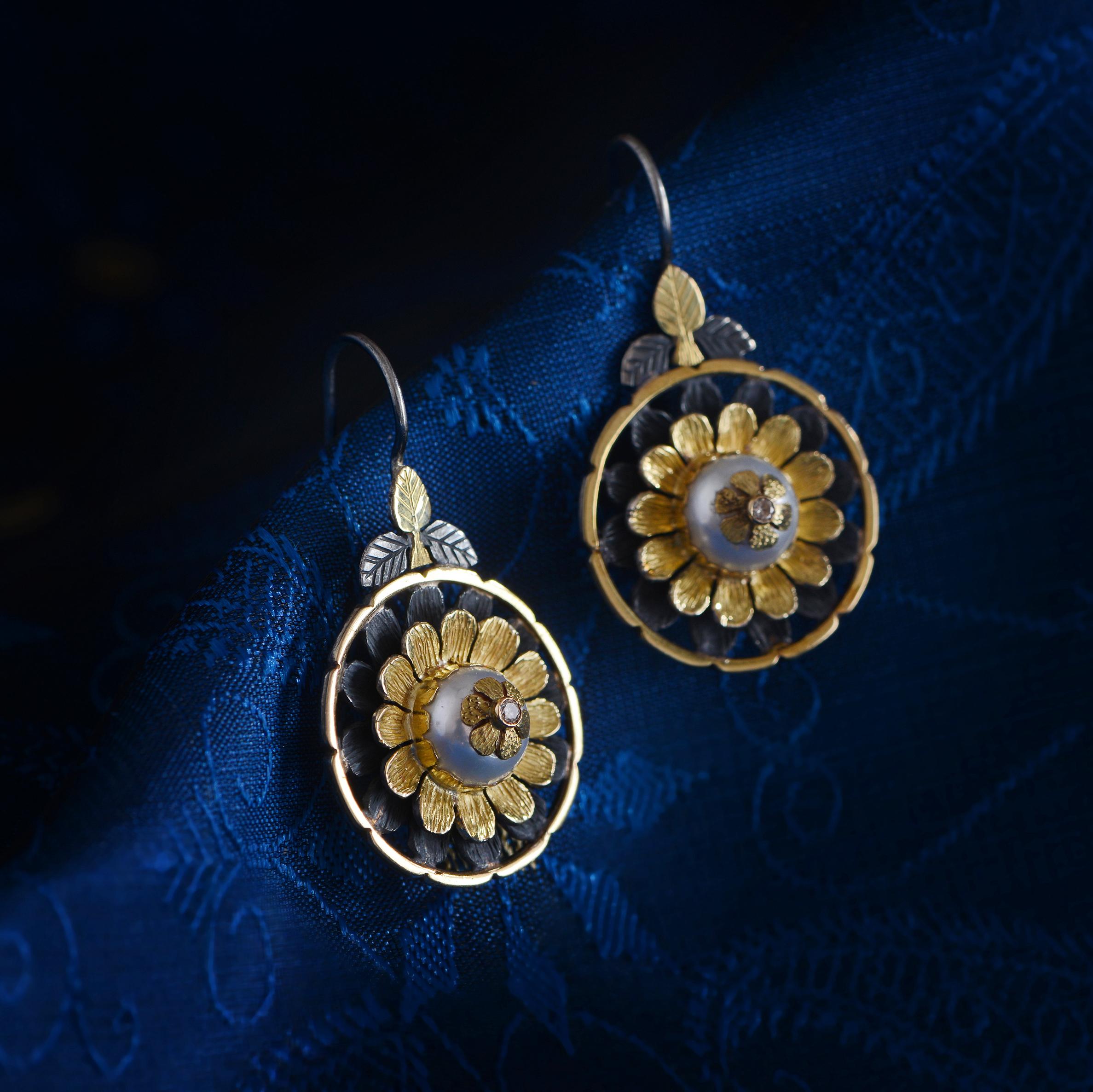 These exquisite one of a kind pearl diamond earrings have been handmade in our workshops.  We have used 18k gold hand engraved botanical motifs and overlaid them onto oxidized sterling silver. The central gemstones are pearls, which are embedded