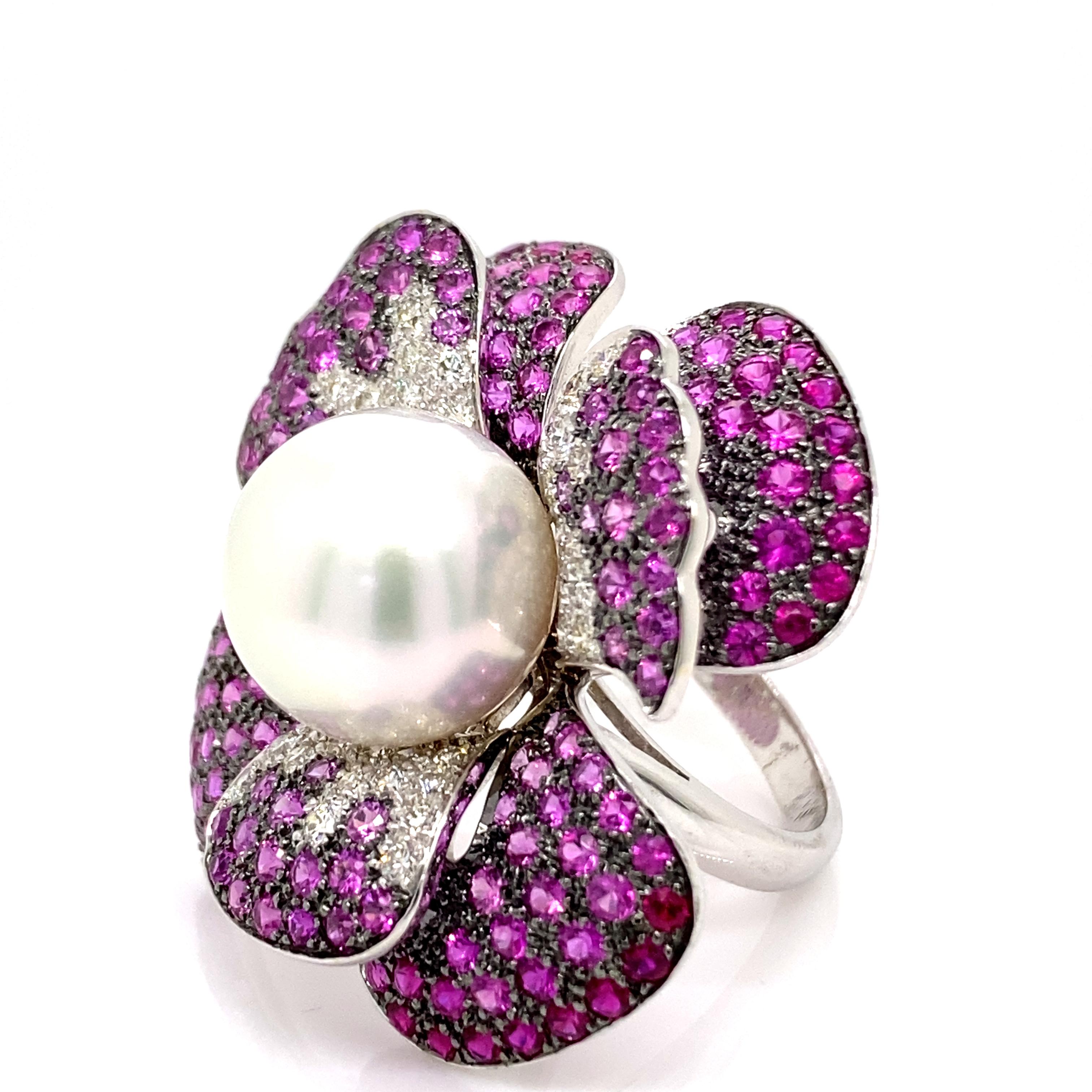 Exquisite and unique multi gemstone floral ring. 
Center South Sea pearl surrounded by 7.15ct of round rubies and 1.10ct of round brilliant diamonds. 8.25ct total gemstone weight set in 18-karat white gold with black rhodium. 
Accommodated with an