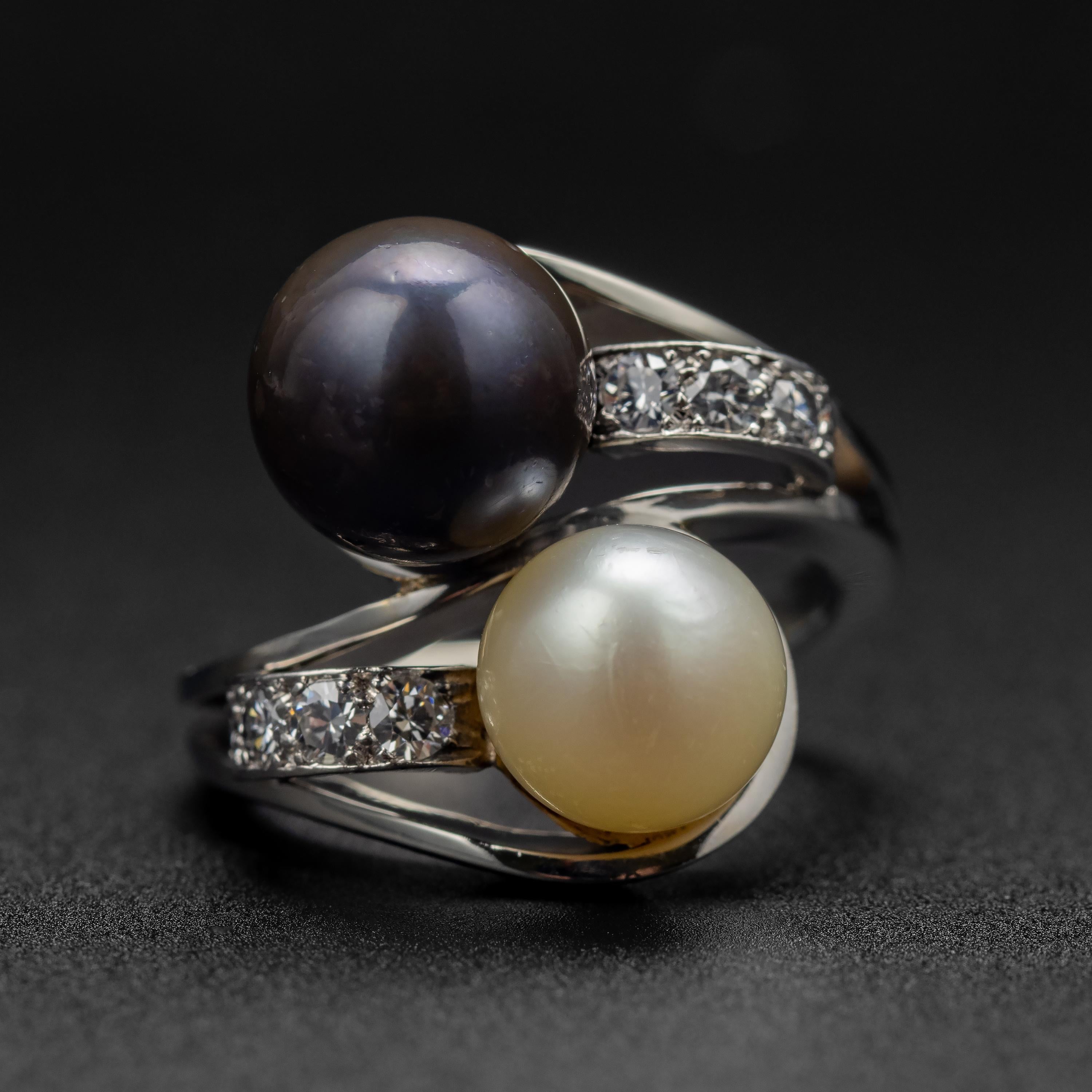 This exceedingly well-made cultured Akoya pearl bypass ring was created from gleaming 18K white gold by the hands of a French jeweler in the 1950s (or thereabouts). The pearls -one creamy white and the other aubergine- measure 8.40mm and 9.48mm.