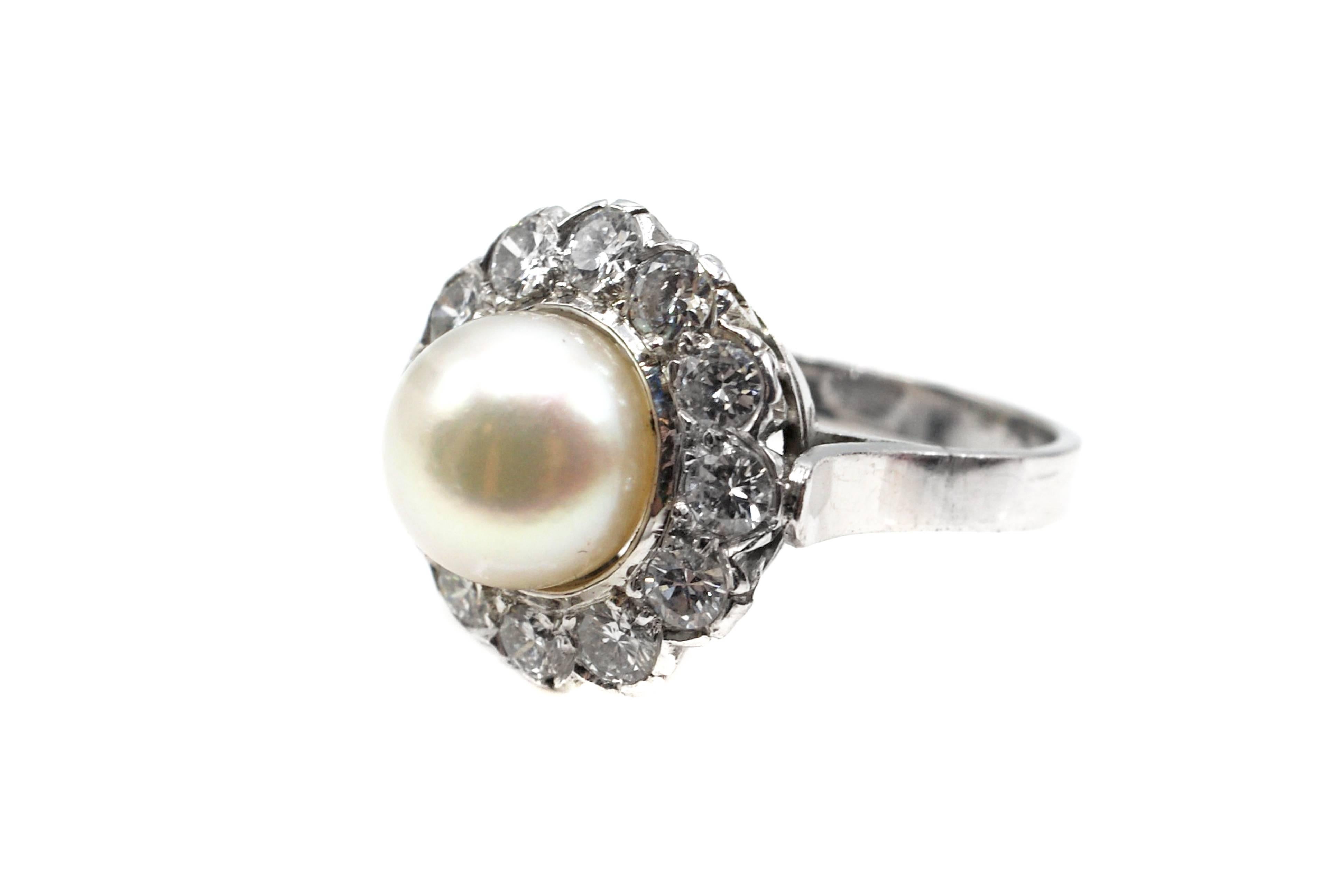 Handcrafted in platinum, this 1960s charming cocktail ring features an 8.25 millimeter lustrous white cultured Akoya pearl. The pearl is embellished by 12 bright weight and sparkly round brilliant cut diamonds weighing approximately 1 carat. The