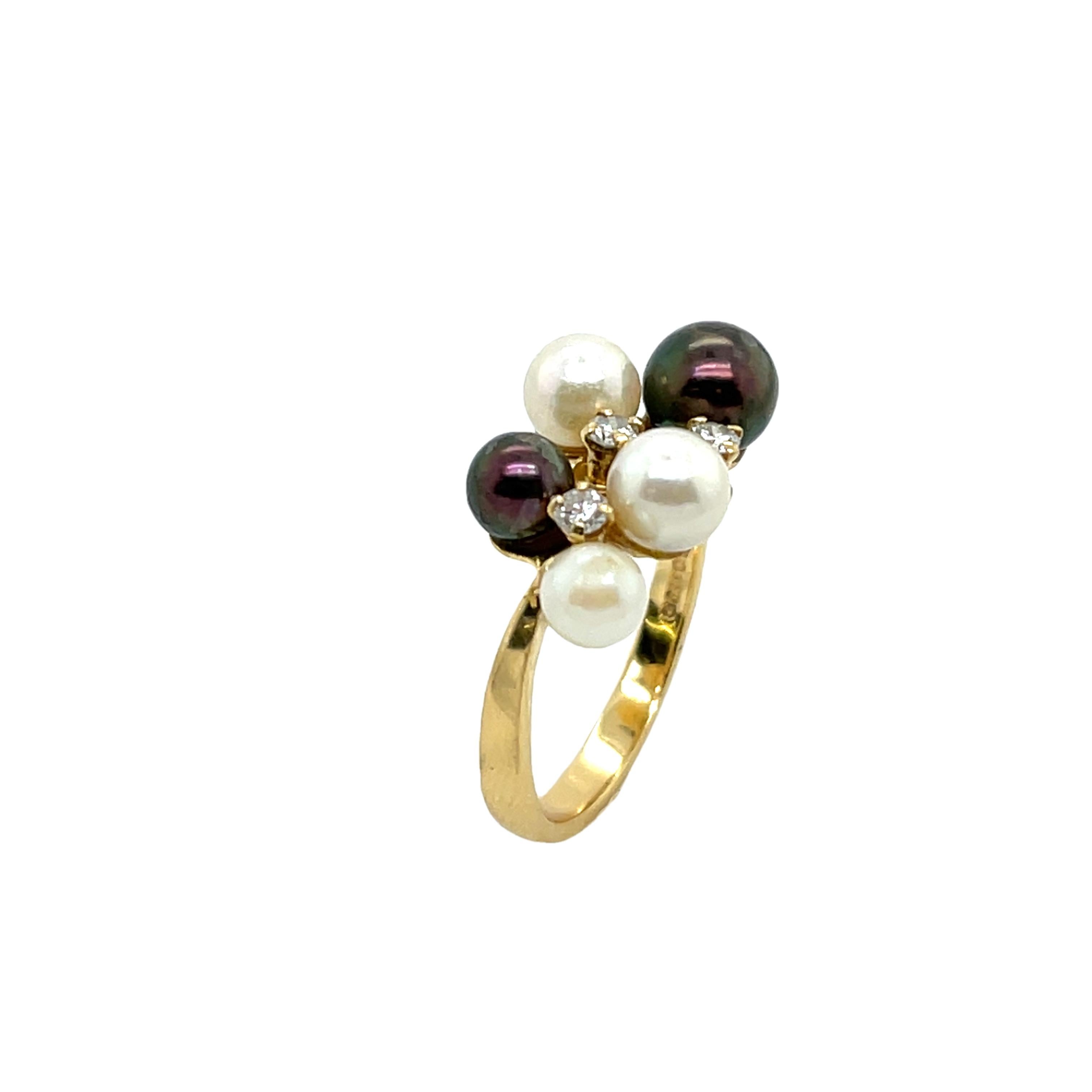 Cette magnifique bague en or jaune 18 carats est ornée de trois diamants ronds et d'un élégant arrangement de trois perles crème et de deux perles brunes. 
Un design unique et sophistiqué mêlant des éléments classiques et modernes.

Poids total des