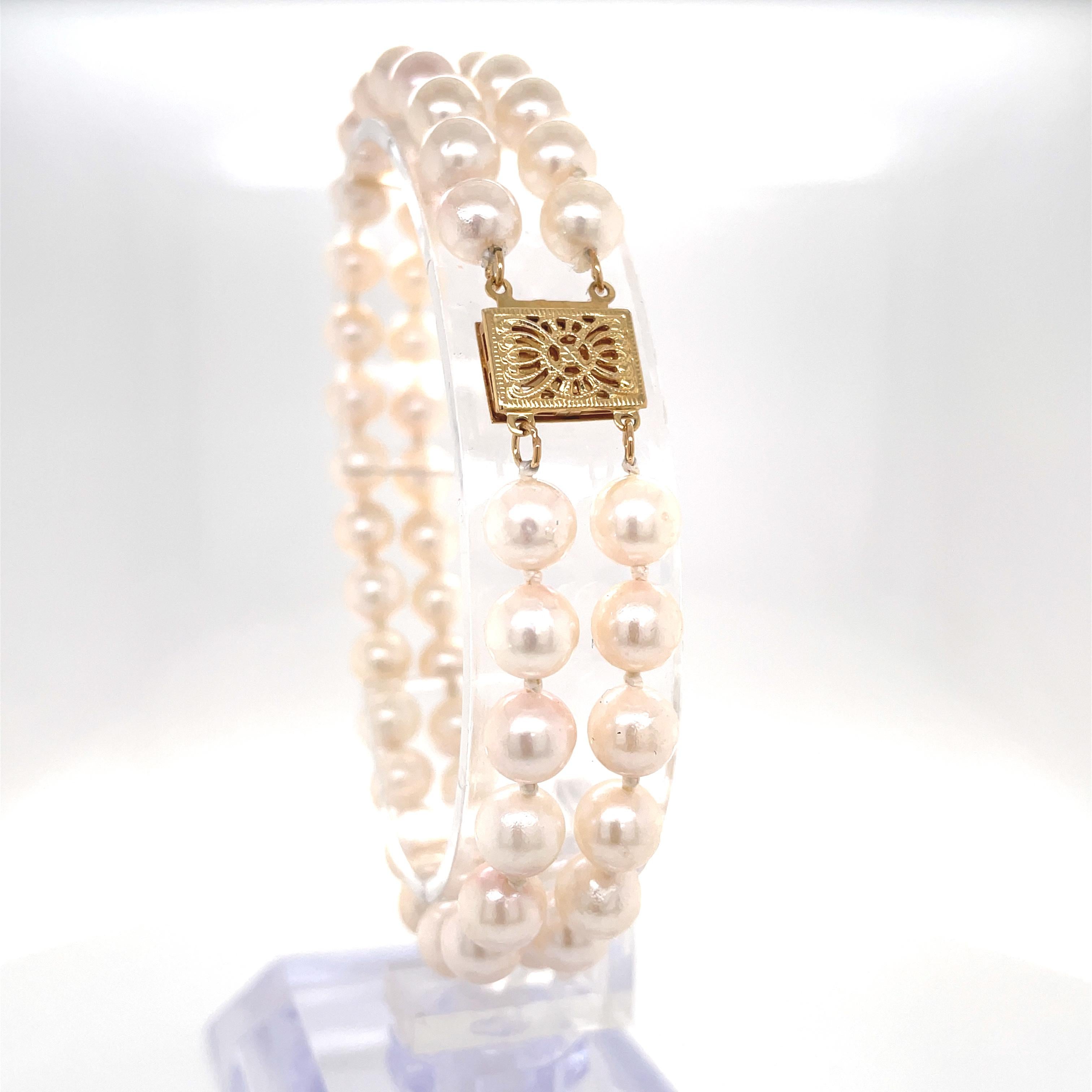 Enhanced with a decorative 14 karat yellow gold filigree charm clasp, this classic double strand bracelet of creamy white pearls presents a fresh modern layered look.
Lustrous pearls measuring approximately 5.8mm - 5.9mm are hand strung and knotted