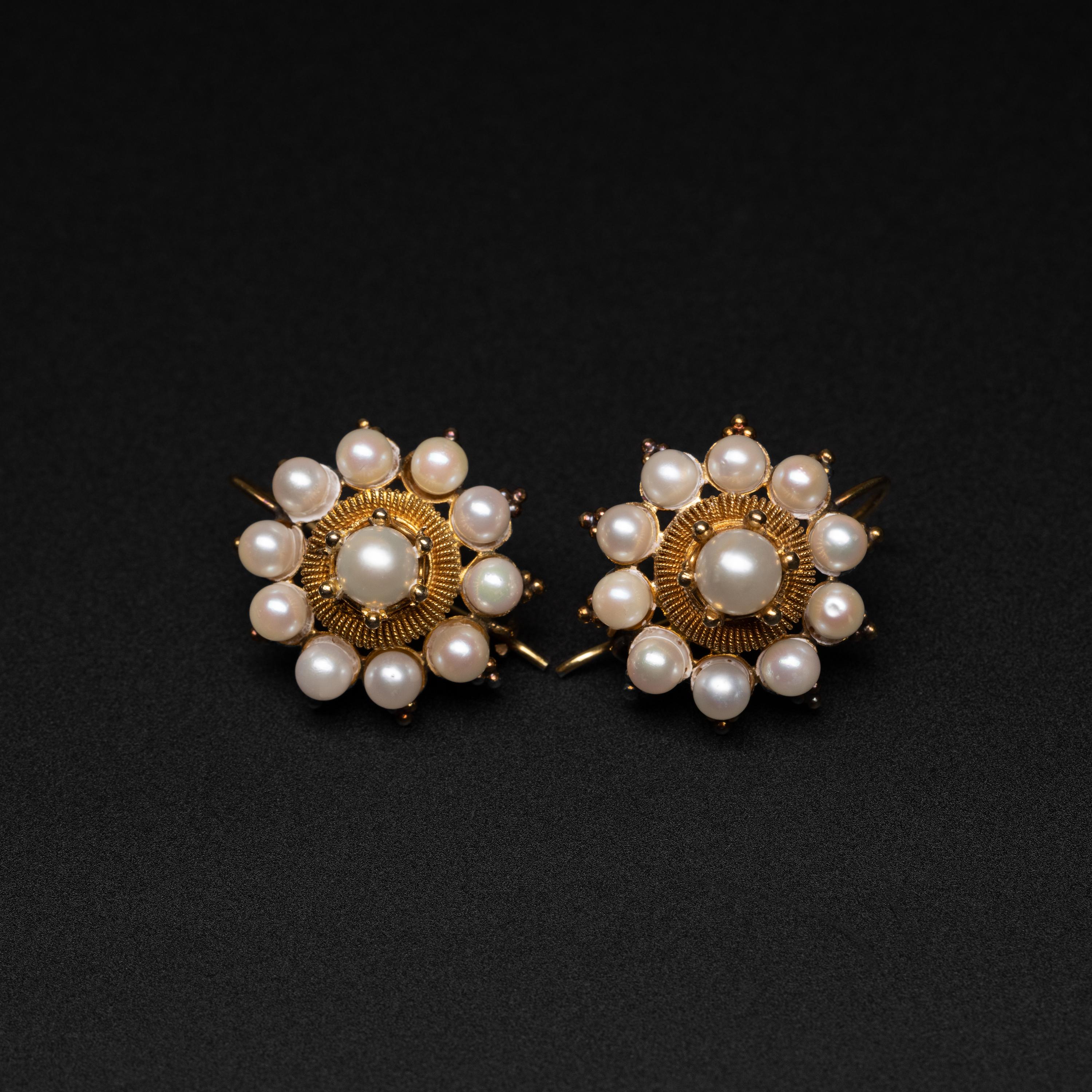 Exquisément fabriquée à la main, cette paire de boucles d'oreilles du milieu du siècle (vers 1950) comporte dix perles Akoya de culture de 4 mm entourant une perle Akoya de 5,9 mm sertie en couronne. Autour de chacune des perles focales se trouve