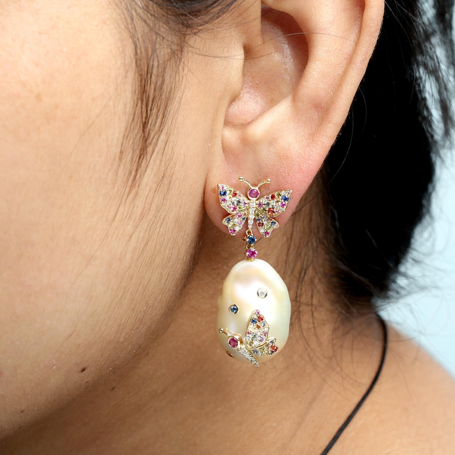 Ces boucles d'oreilles étonnantes présentent des perles lumineuses associées à des motifs de papillons complexes sertis de saphirs arc-en-ciel et rehaussés de diamants étincelants. Le design allie l'élégance à une touche fantaisiste, ce qui les rend