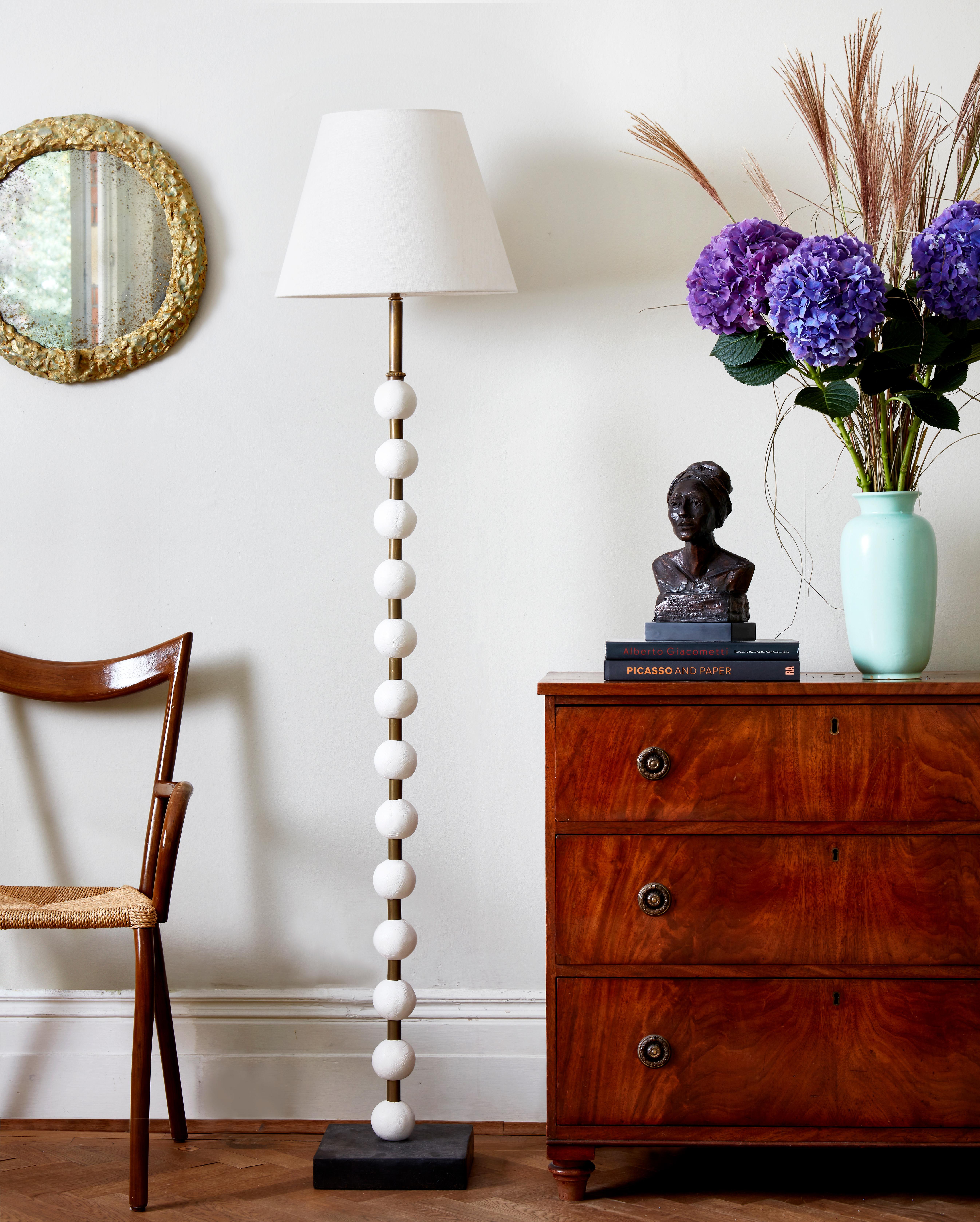 This contemporary Margit Wittig floor lamp is mounted on a slate base and features multiple white resin handcrafted spheres. Each element is hand patinated to increase tonal contrast and enhance the surface texture.

This statement piece which will