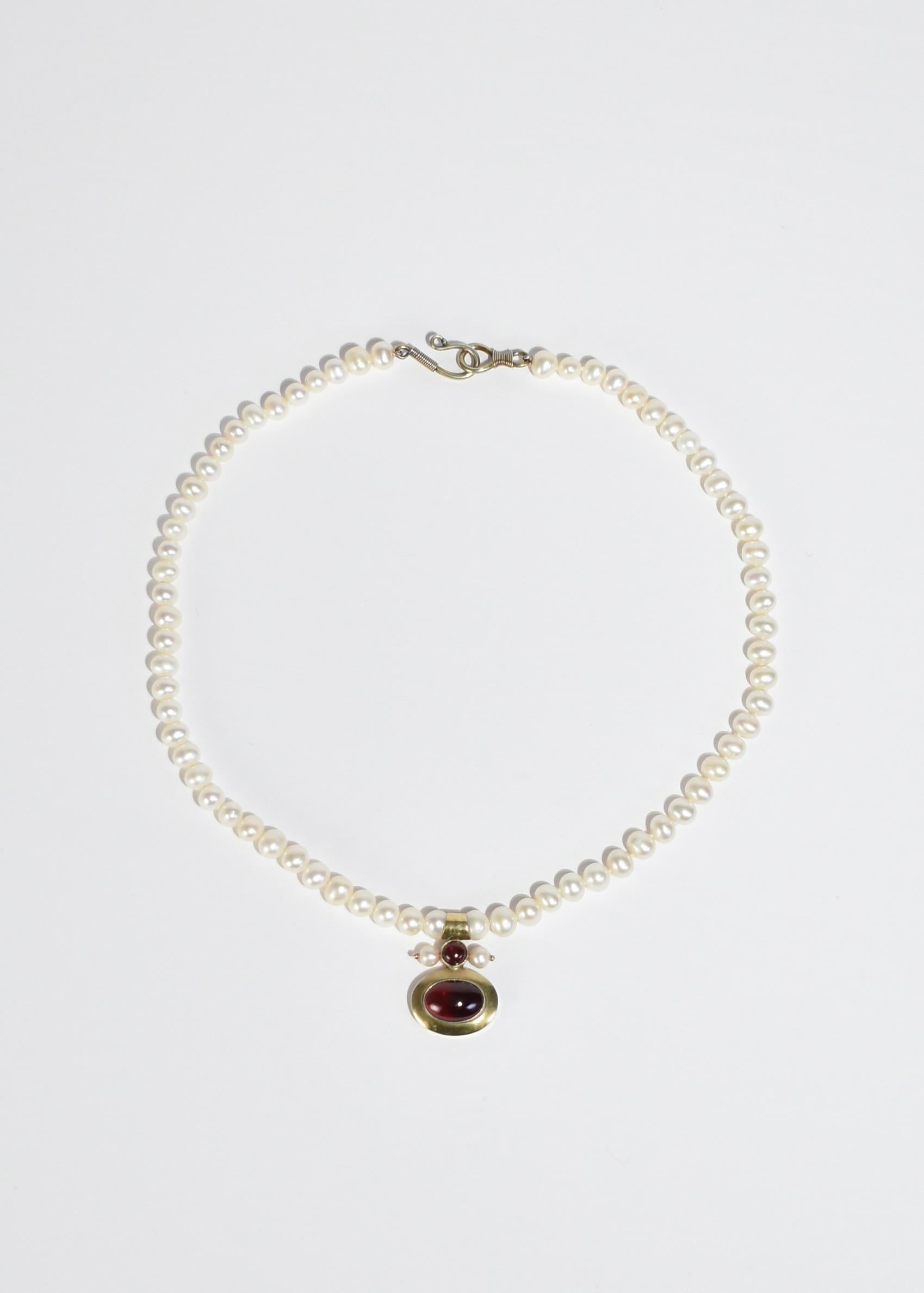 Vintage pearl necklace with gold garnet pendant, hook and eye closure. Stamped MMA 925. 

Material: Sterling silver, gold vermeil, pearl, garnet.

We recommend storing in a dry place and periodic polishing with a cloth.