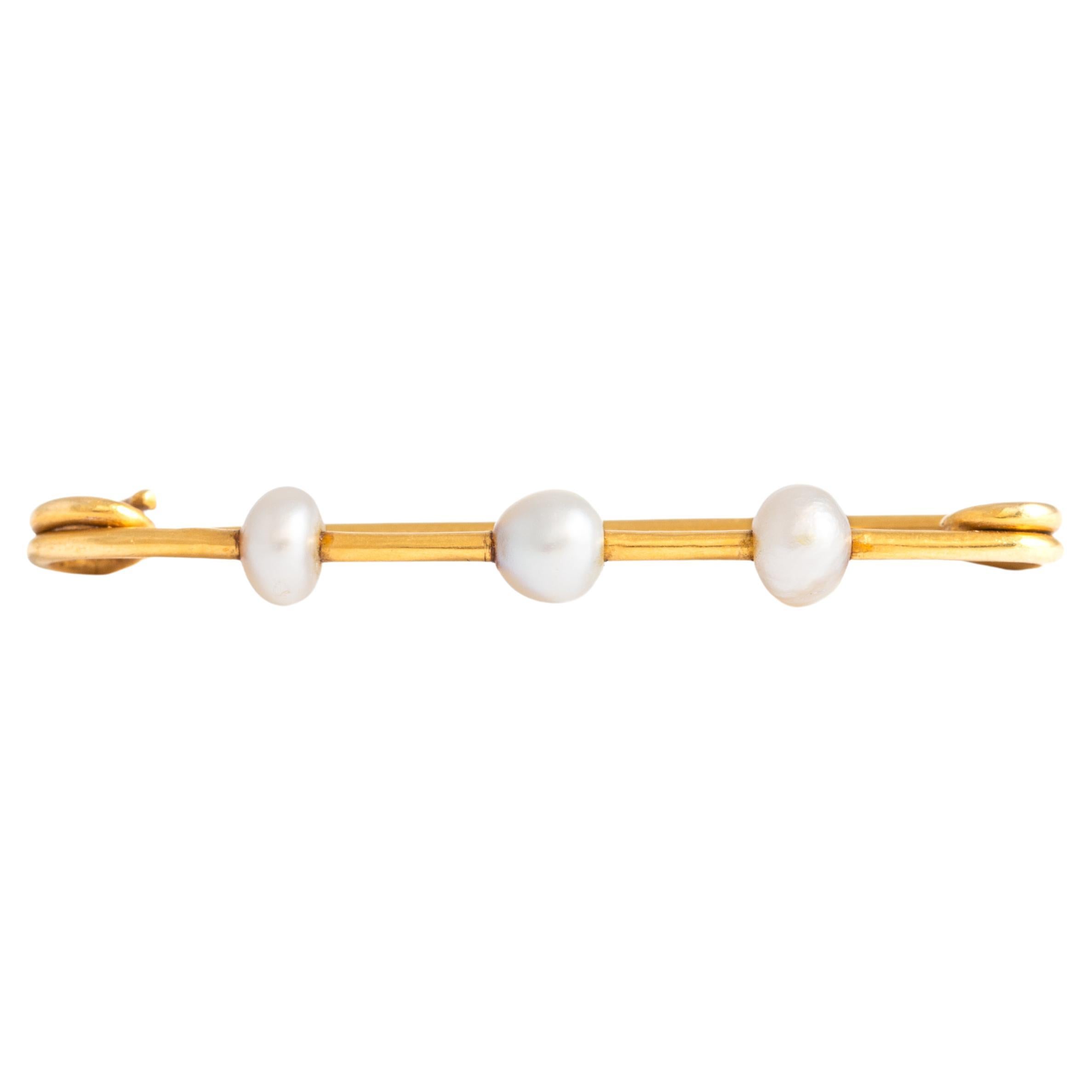 18K yellow gold brooch forming a safety pin with three cultured pearls.
Length: 4.20 centimeters. 
Gross weight: 2.40 grams.