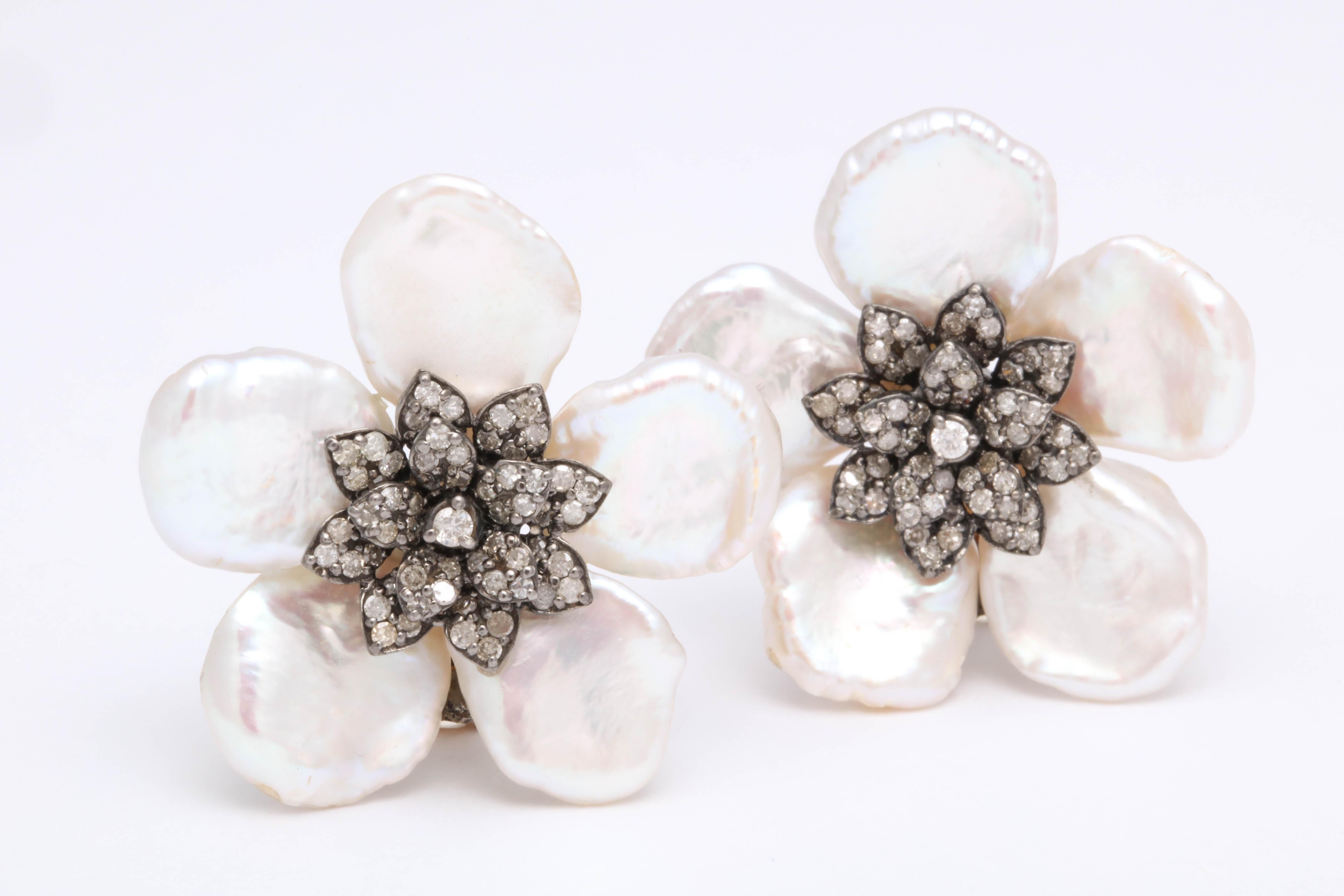 
A fashionable and wearable earring in a classic design. 

Diamond center flower with 1.74 carats of diamonds surrounded by 5 pearl petals. 

Approximately 1.20 inches in diameter, set in silver 

For pierced ears but can be adjusted to clips if