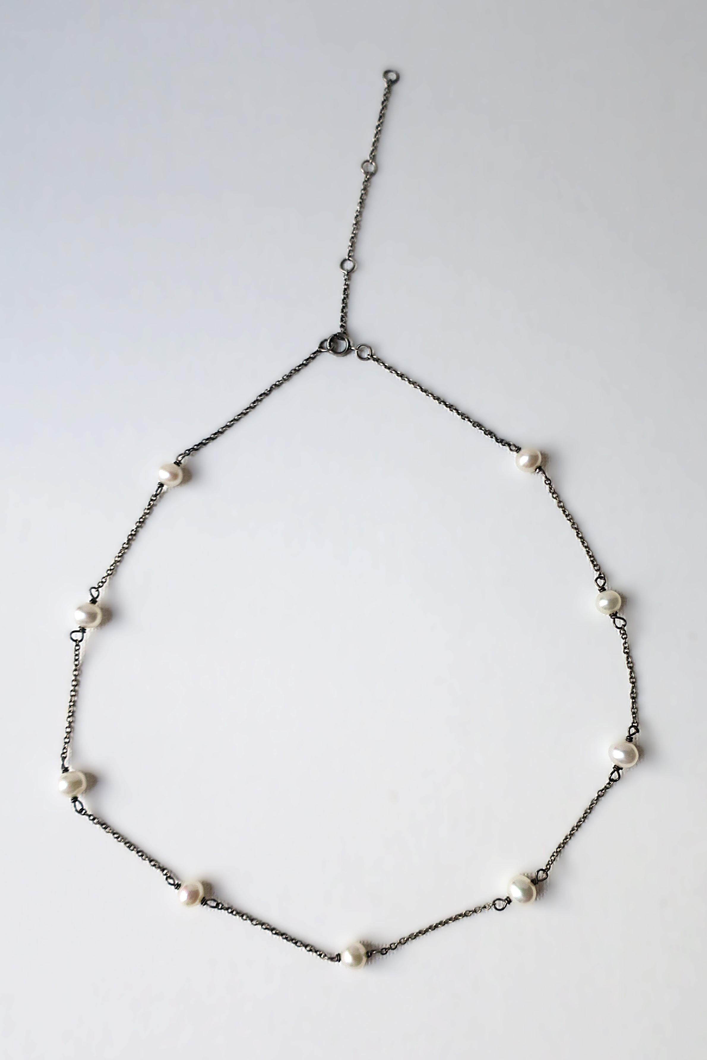 Una collana di perle su catena in argento sterling con quattro/cinque diverse opzioni di lunghezza. Nove (9) perle bianche d'acqua dolce su catena d'argento. Indossalo alla lunghezza massima, alla clavicola o a girocollo. Indossala da sola o