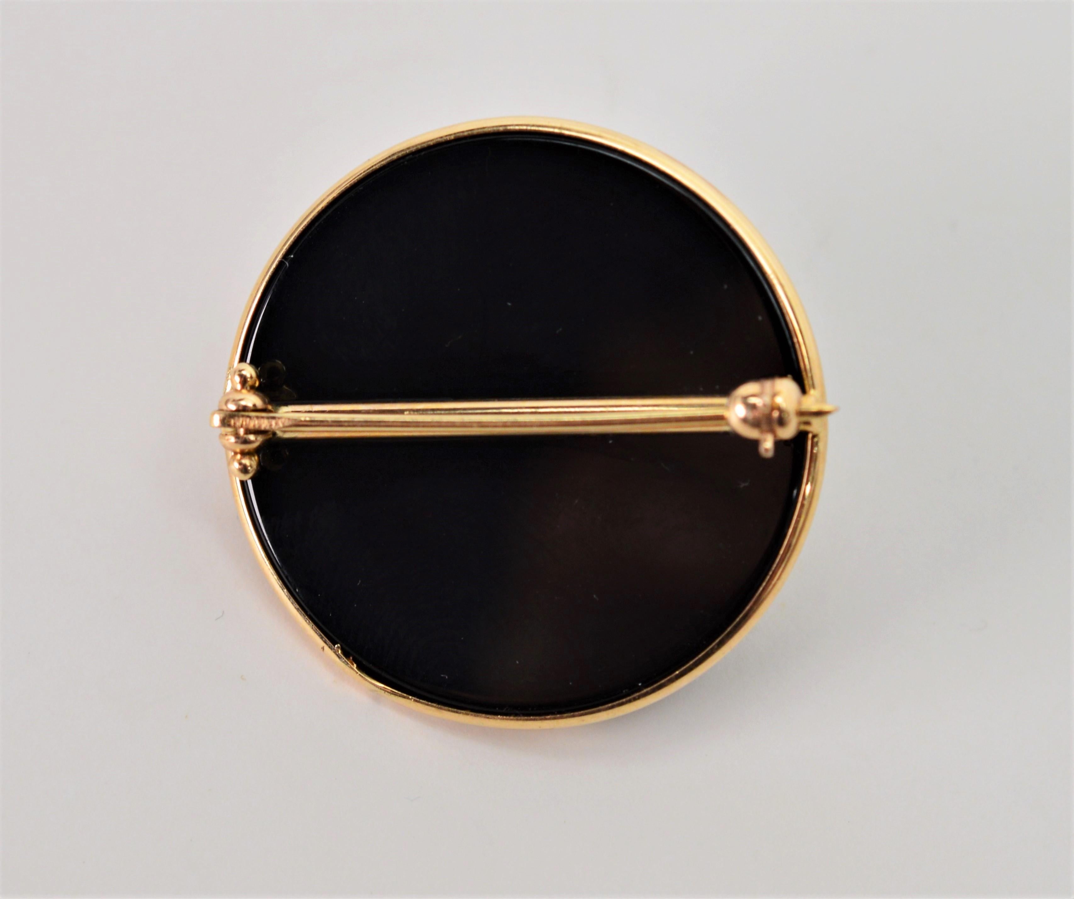 A classic combination of black, white and gold present beautifully in this emblem brooch. A 13.5 mm mabe pearl center is framed in black 
oynx and trimmed with fourteen carat gold enhancements.  This pin measures 1-1/8 inch in diameter. A great