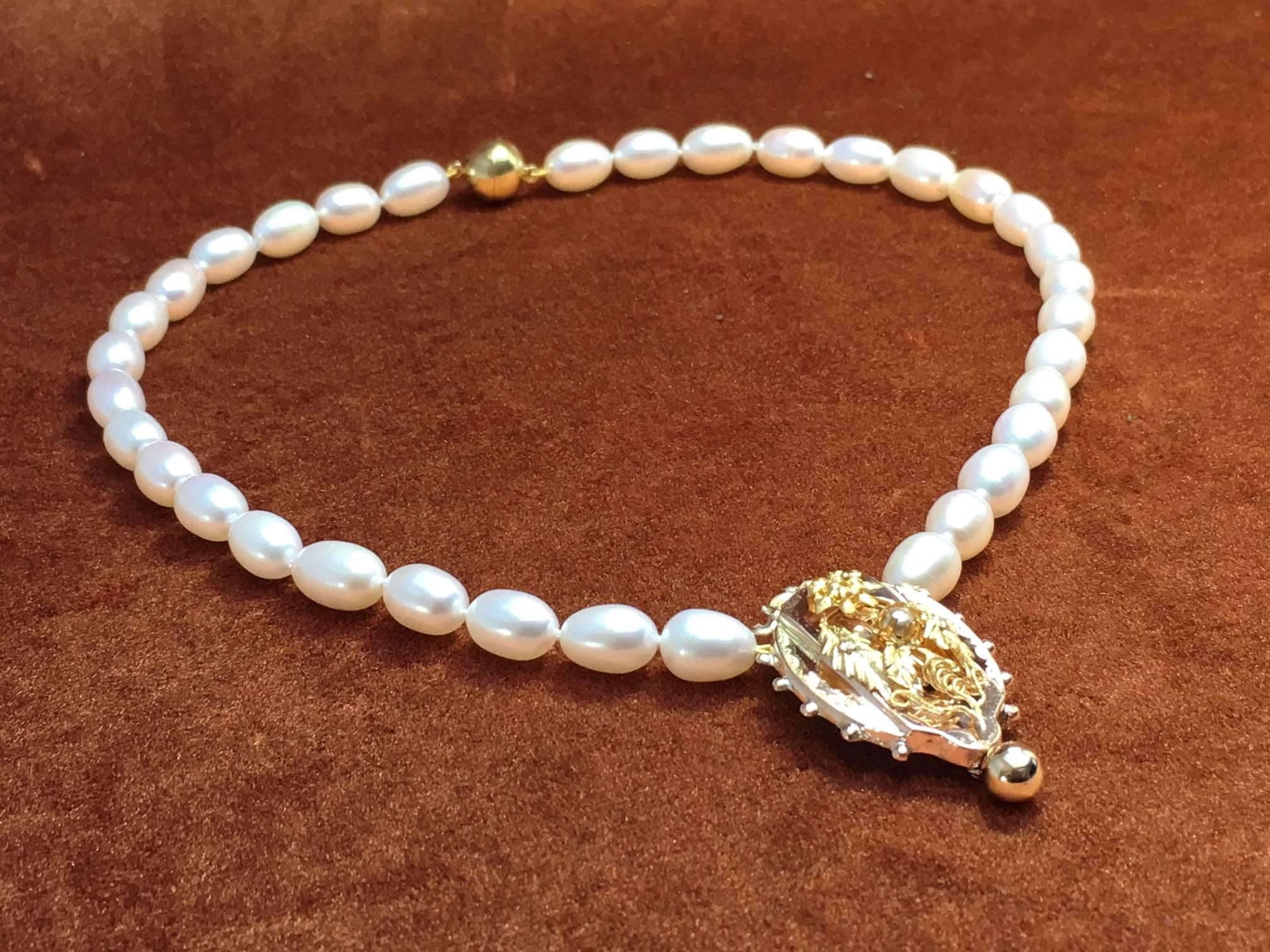 Pearl necklace with antique 14 carat pink and yellow gold ornament made from antique gold brooch. 

This necklace is made from an original old brooche, made in 1880. The details of this ornament will attract the eye of the connoisseur of antique