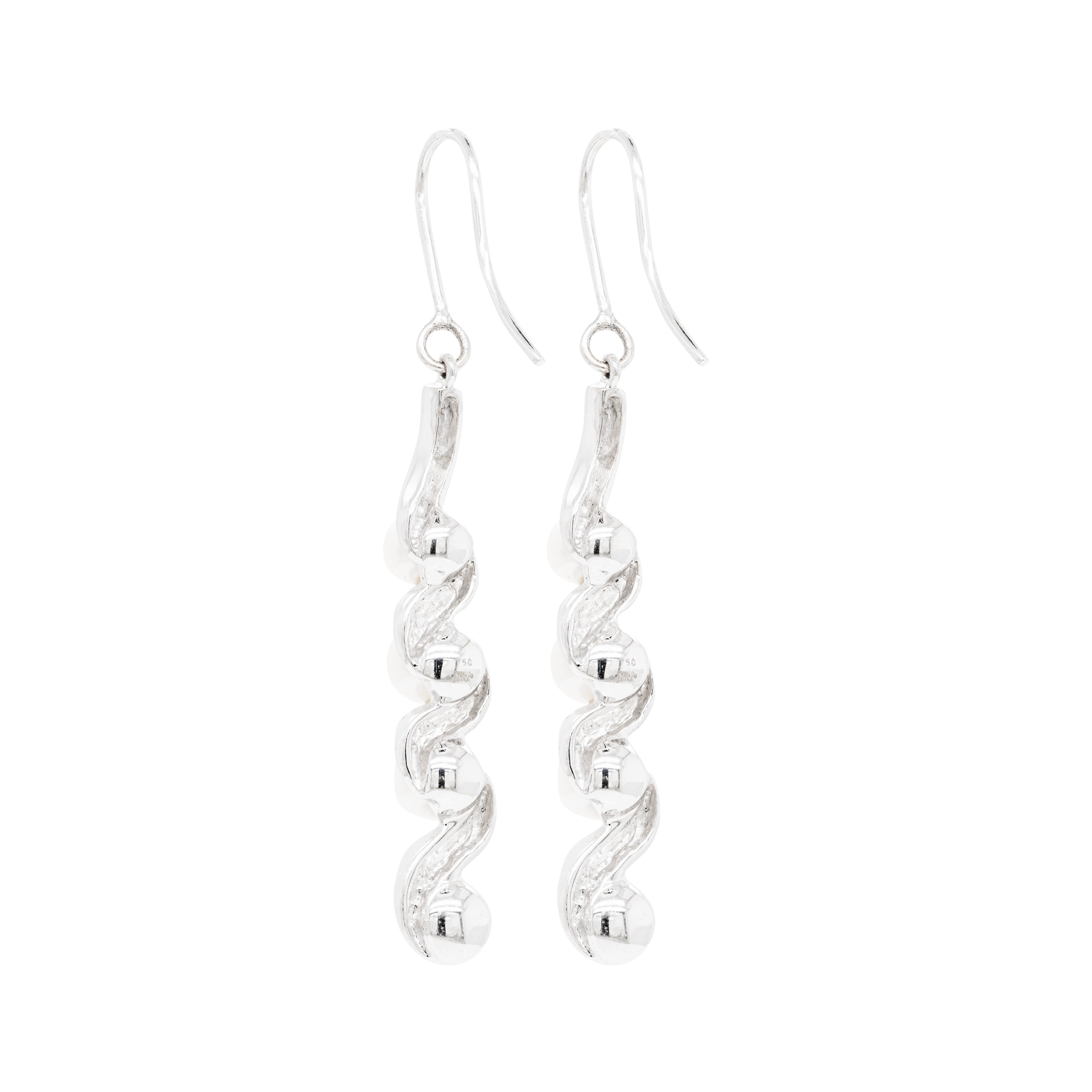 Elegant and beautiful, these drop earrings are designed with alternating black and white round brilliant cut diamonds set in 18 carat white gold swirls. Each piece features four cultured pearls measuring from 4.4mm to 6.1mm, delicately highlighting