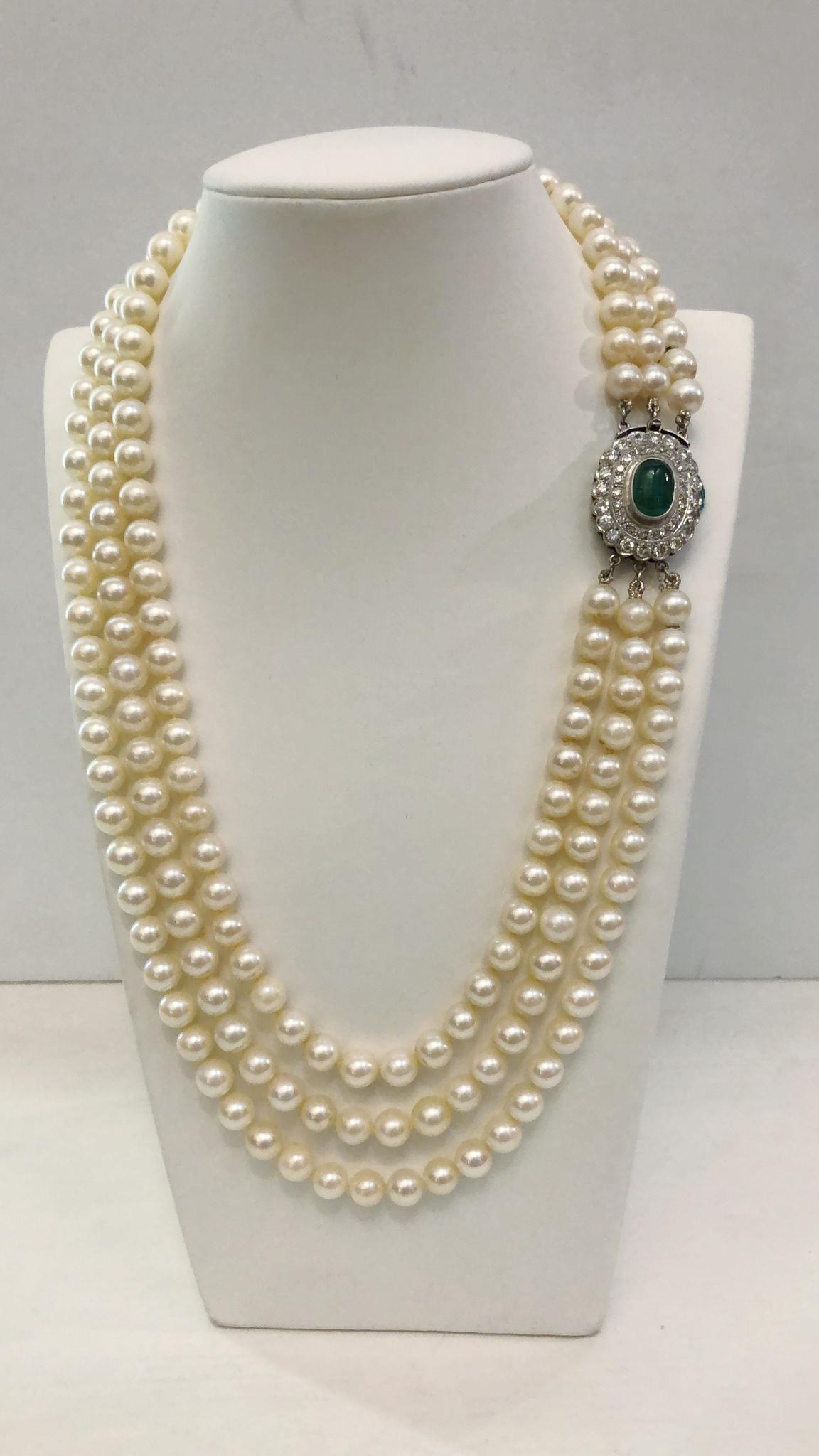 Vintage Italian necklace with three strands of 7.5/8 mm pearls, the closure in 18 karat white gold with a central cabouscon emerald of 3.00 carats and double rows of brilliant diamonds for a total of 3.00 carats / Made in Italy 1950s
Length 50cm