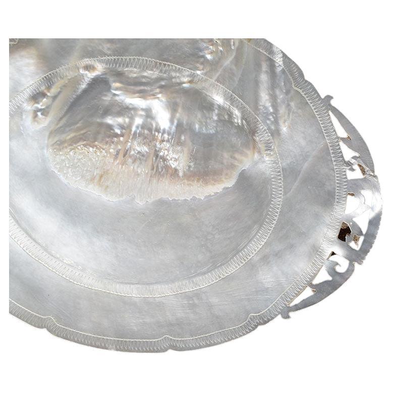 An unusual pearlized capiz shell trinket dish or catchall. We've never come across anything similar to this beautiful plate. It is oval in shape and is decorated with decorative pierced edges. It is made of a natural pearlized or capiz material.