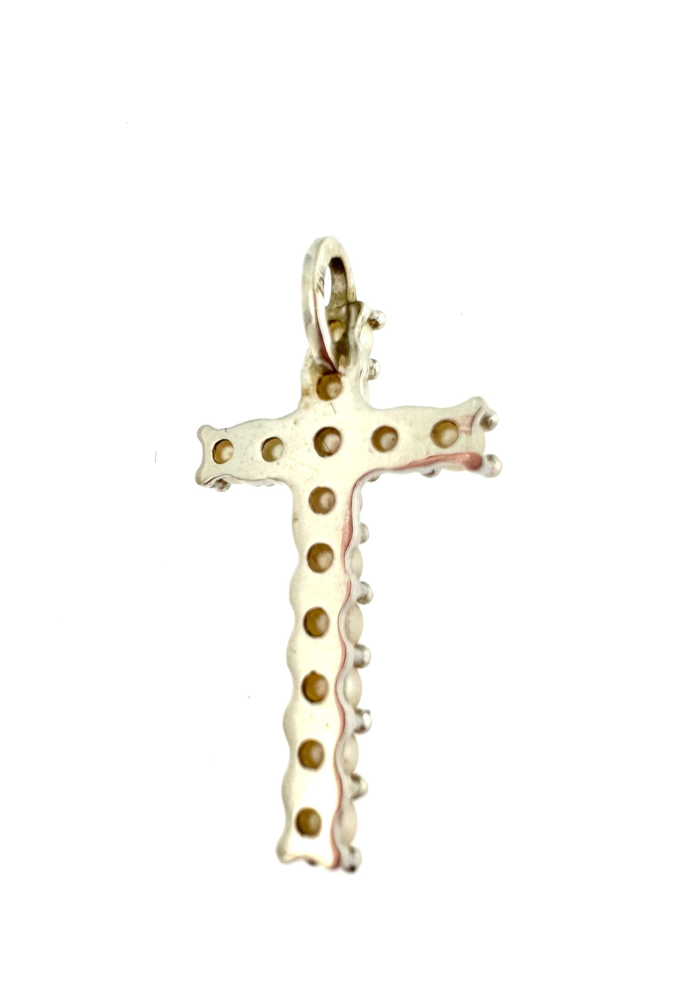 Swiss 18kt white gold cross decorated with 13 embedded round white pearls. Pearls are natural gems produced by the pearl oyster and the freshwater pearl mussel. In Japan pearl hunters have been diving without breathing equipement for around 2000