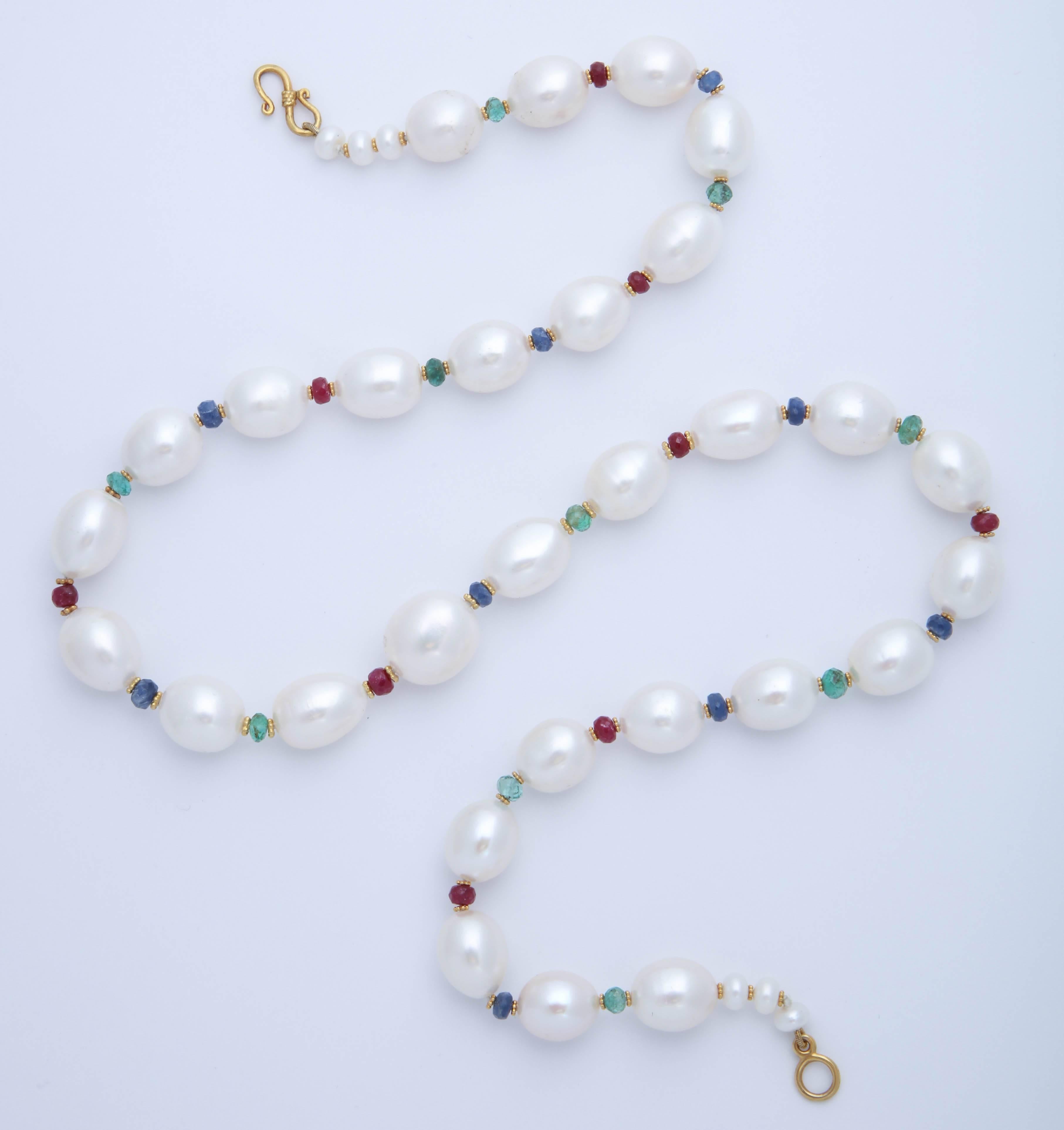 These beautiful oval freshwater pearls and interspersed with faceted emerald, ruby, and sapphire beads. On either side of the precious stone beads are 18 kt rosettes plated with 24 kt gold to give them a rich yellow color. The  necklace is finished