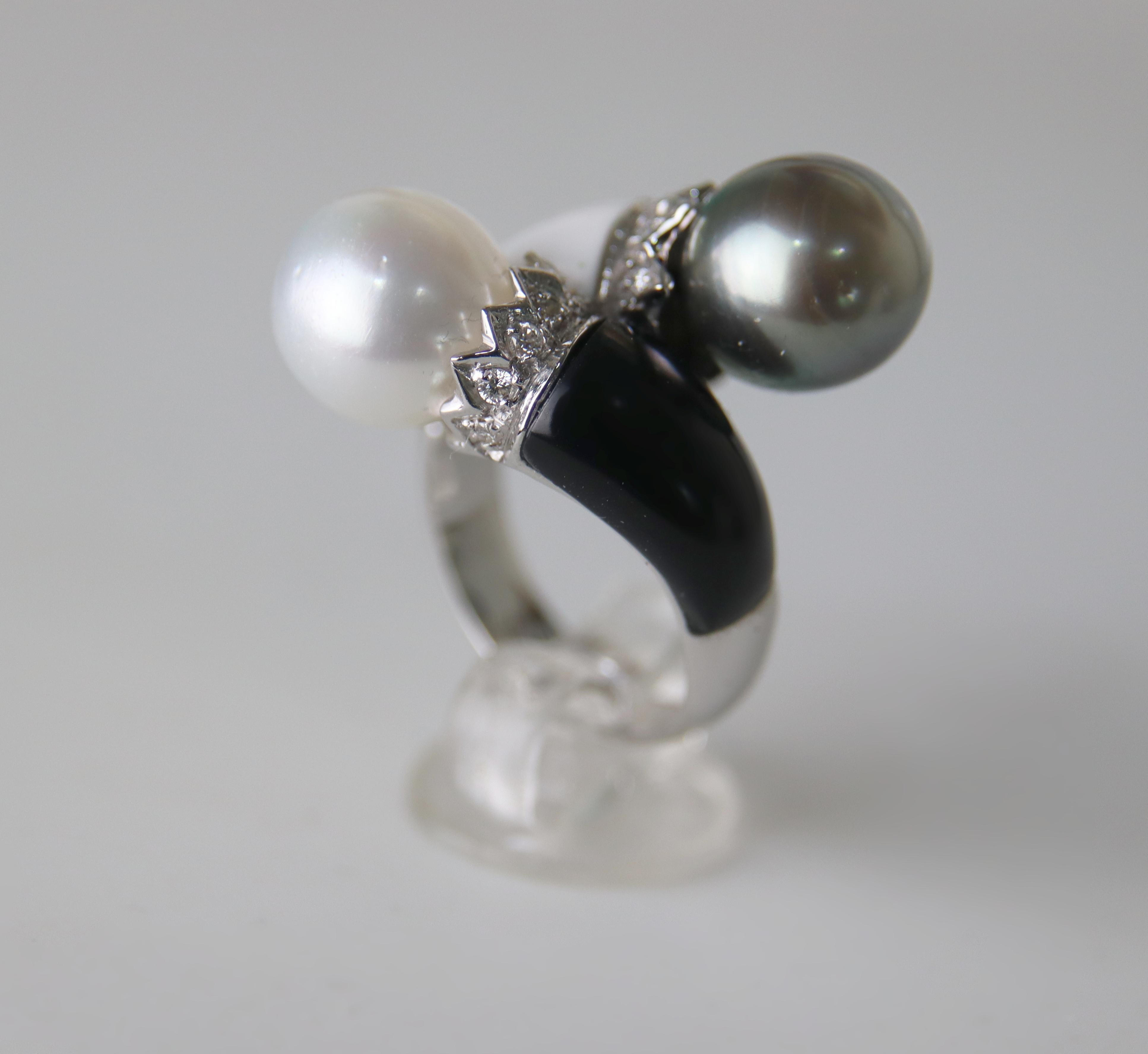 Dieser exquisite Ring aus 18 Karat Weißgold verkörpert die perfekte Balance zwischen zeitloser Eleganz und zeitgenössischem Design. Sie wird von Hand gefertigt und besteht aus zwei außergewöhnlichen Zuchtperlen - einer weißen Perle mit leuchtendem