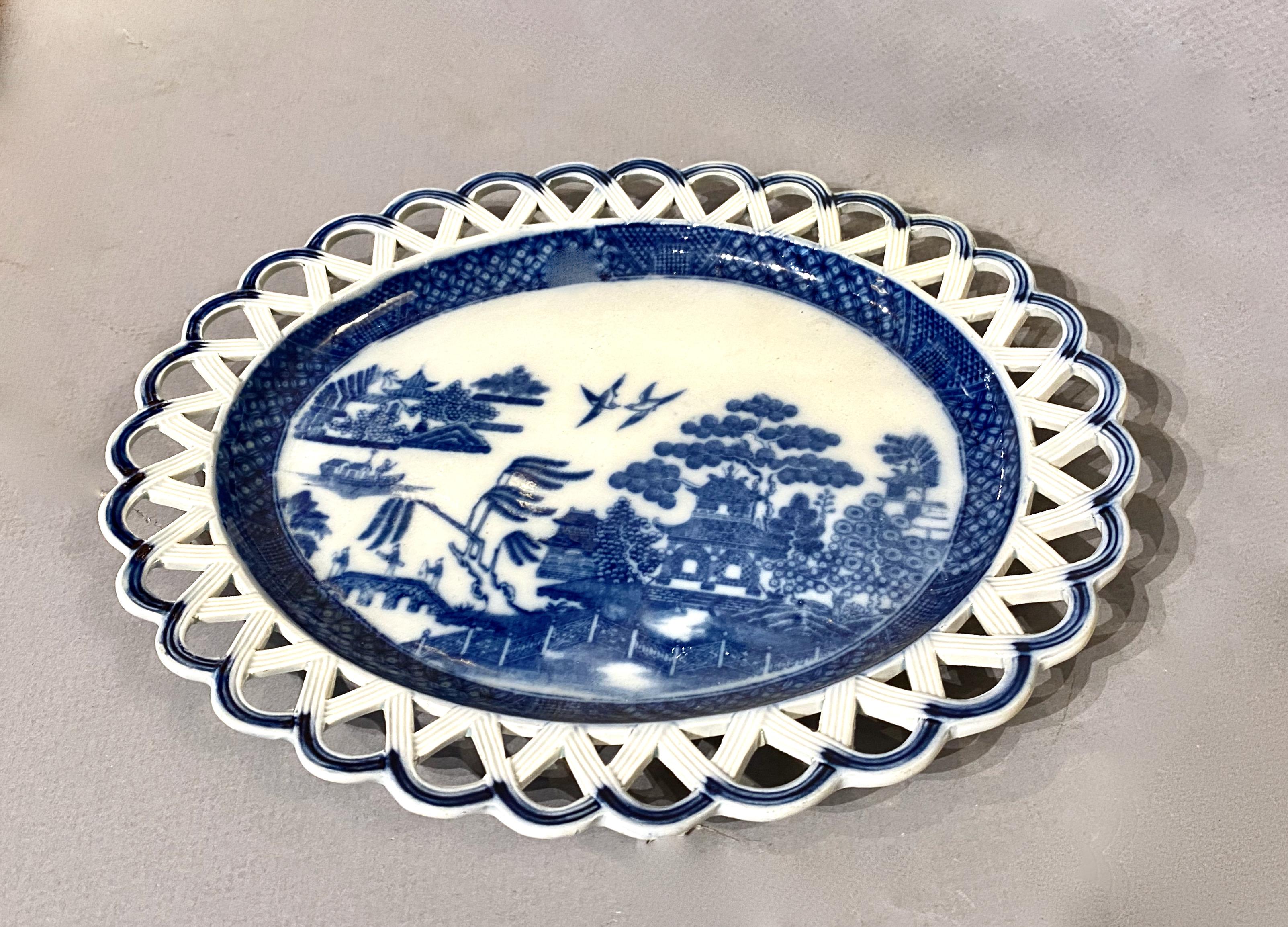 This is a good example of a late 18th c. or early 19th c. pearlware blue and white small serving platter or underplate. The platter features a reticulated border with a blue and white transfer border encircling a 