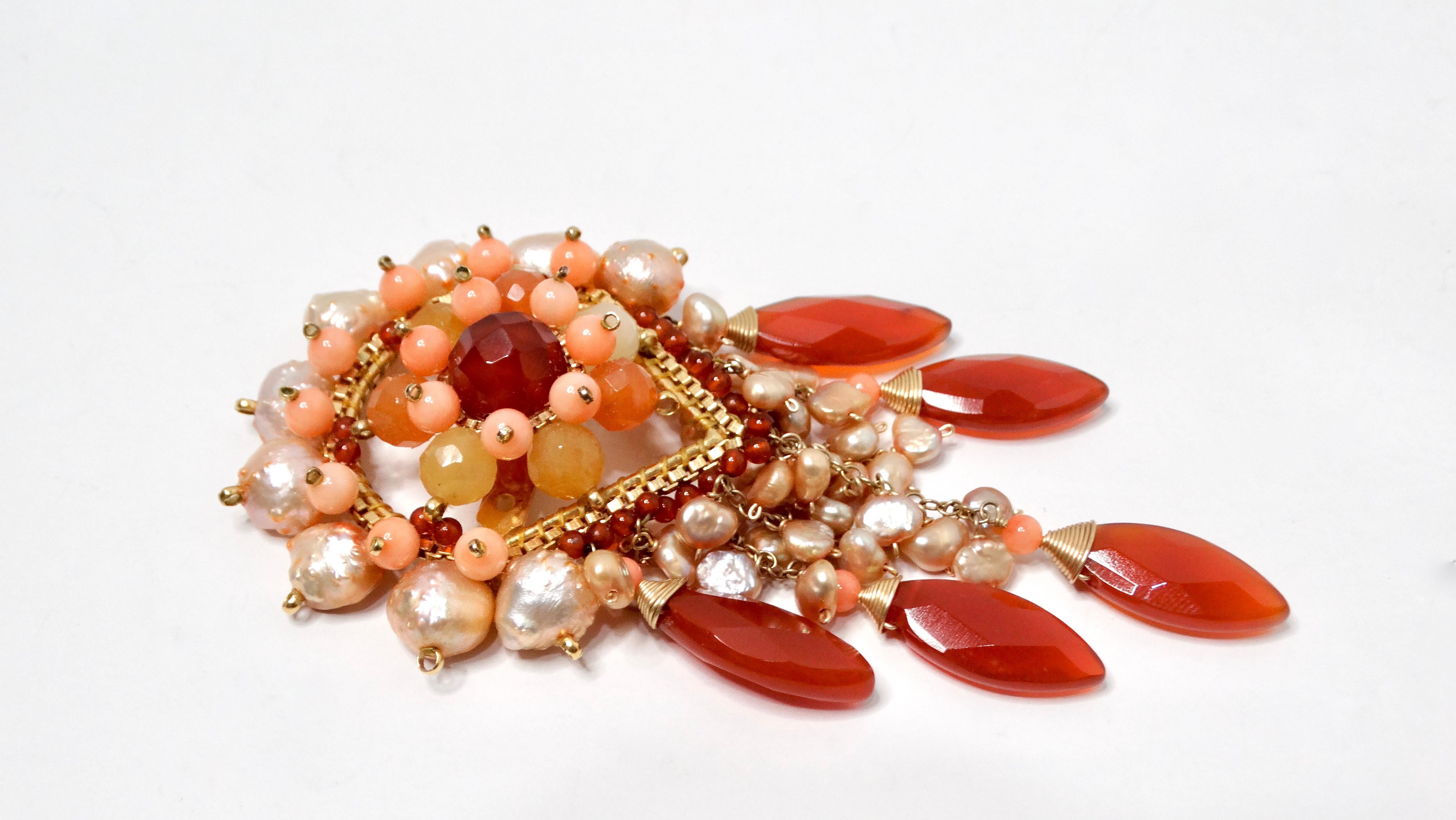 Ti presentiamo la Spilla Pearly Intricate Beaded Pink & Orange Dangling, un pezzo squisito che cattura magnificamente l'essenza di un acchiappasogni. Il suo design delicato è caratterizzato da un'armoniosa miscela di tonalità che vanno dal pesca