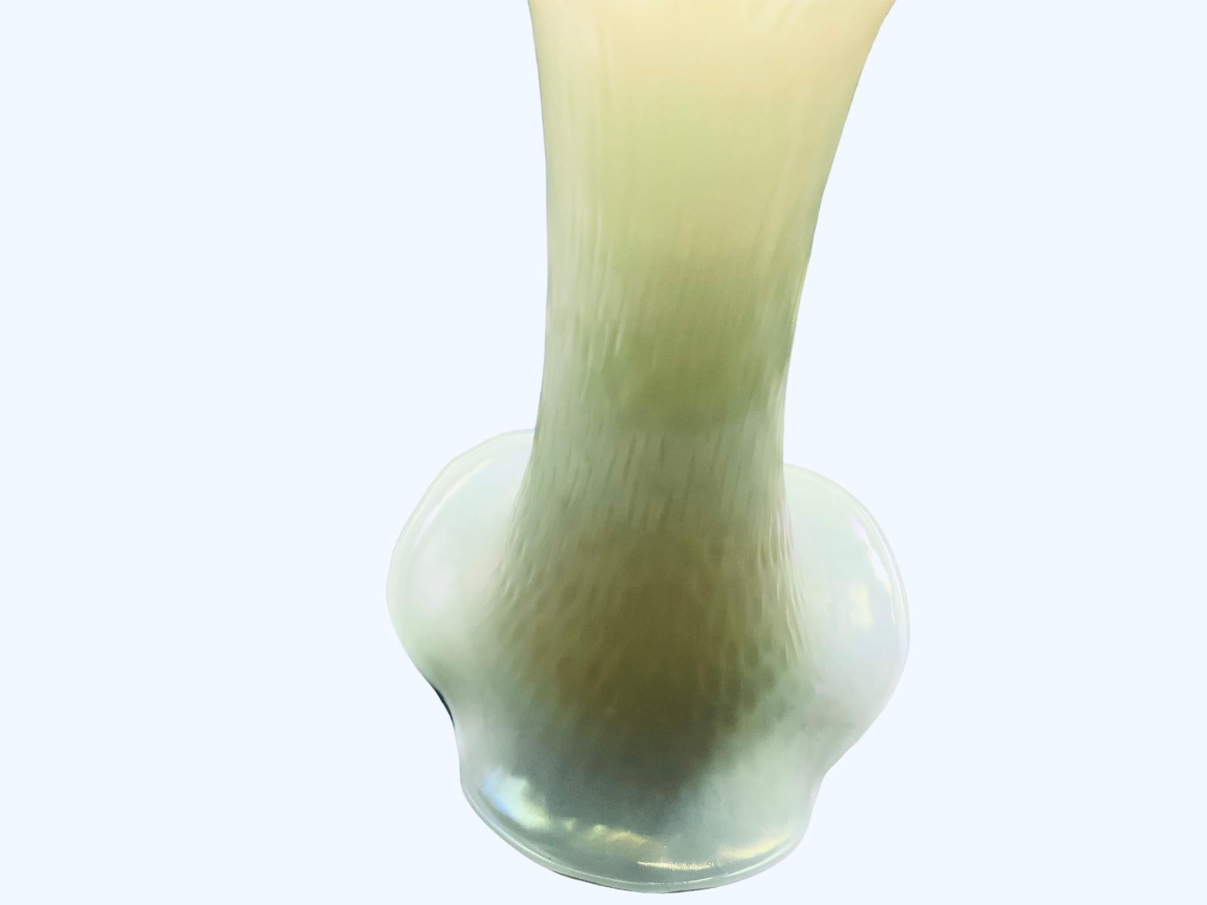 This is a medium size Art Glass flower vase. It depicts a  pearly opaline glass flower vase with wide ruffles upper border. The whole vase is adorned with “rainy drops” marks.