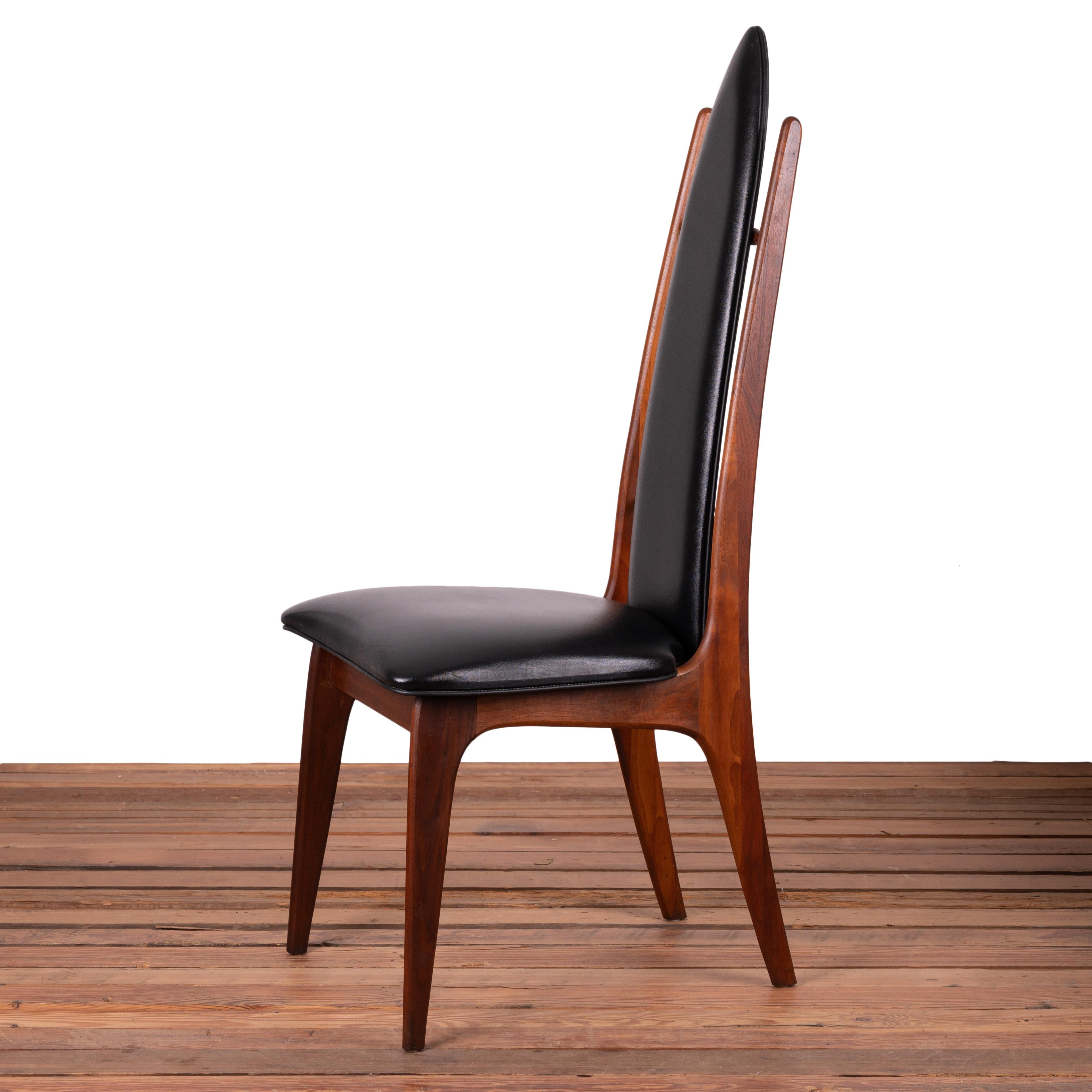 A set of 4 dining chairs in the manner of Adrian Pearsall, mid-20th century.

Walnut with black vinyl upholstery.

17 ½ inches wide by 22 inches deep by 46 ¼ inches tall

