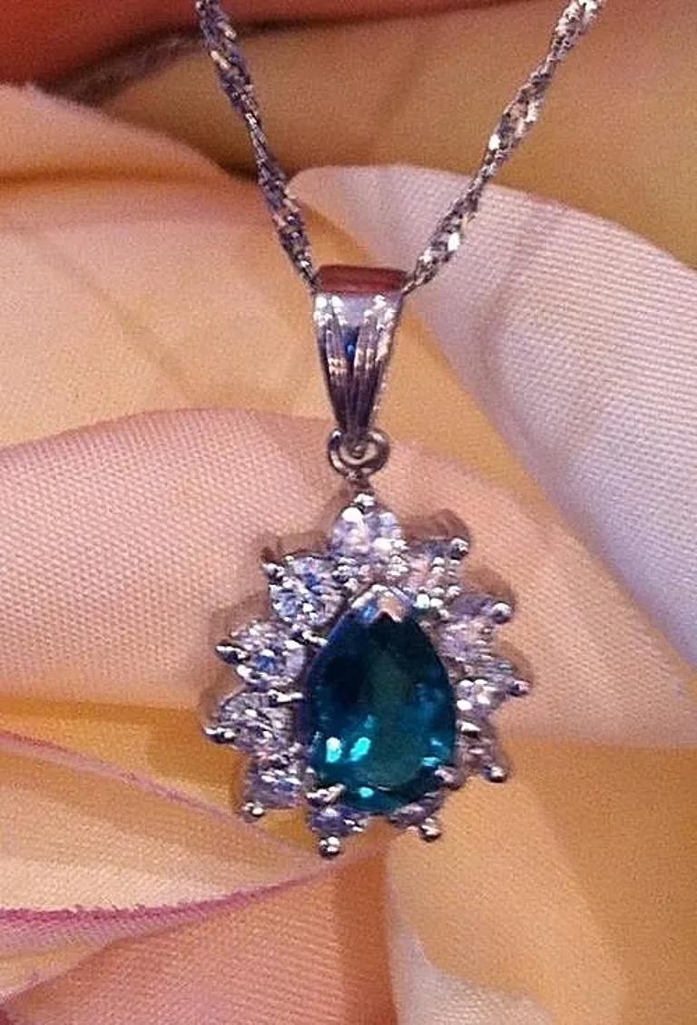 Collier pendentif halo en émeraude et diamant en platine

Le collier pendentif émeraude et diamant en forme de halo présente une émeraude en forme de poire d'une belle couleur vert foncé brillant pesant 1,90 carats sertie au centre, entourée de 11
