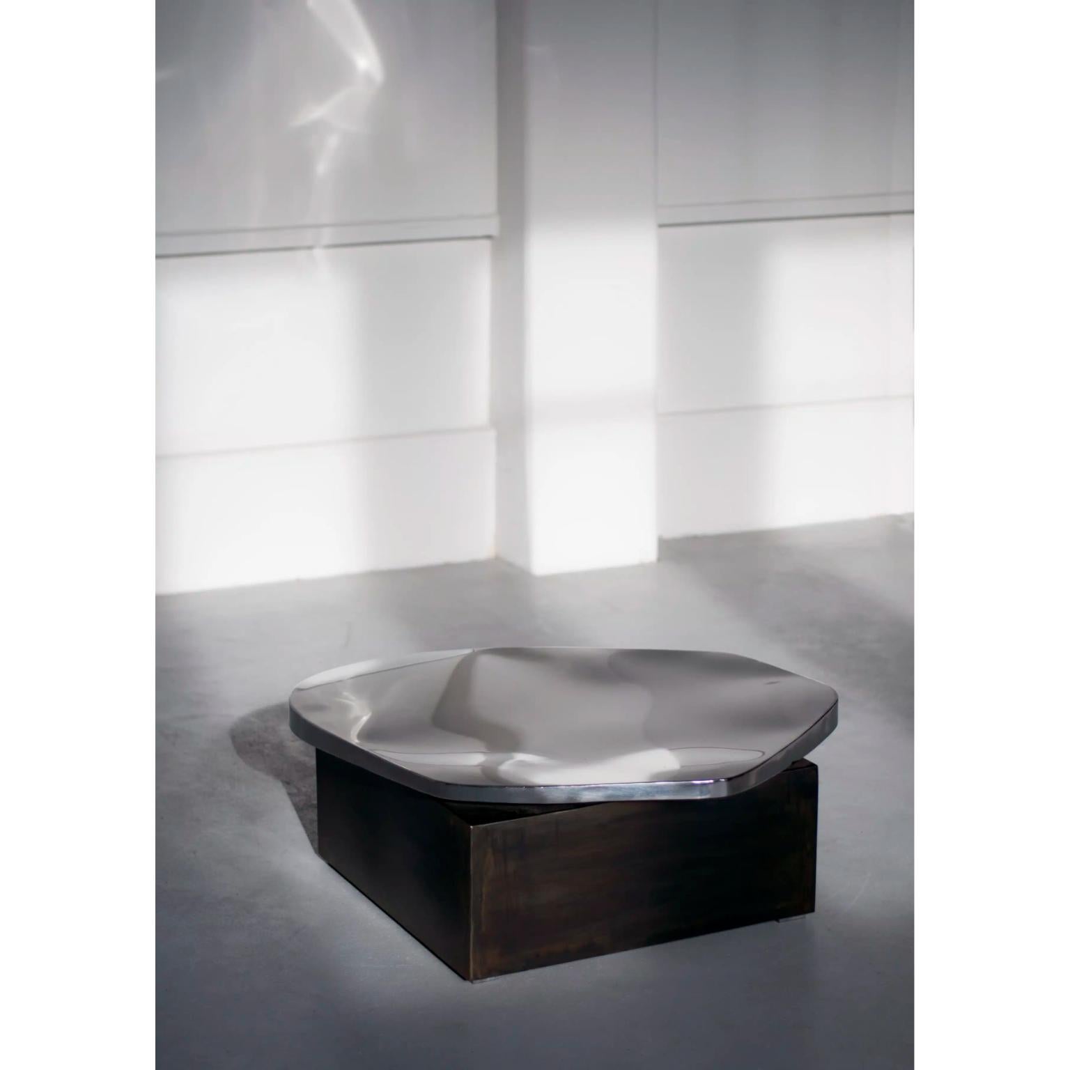 Table basse Pebble de Pol Quadens 
Édition limitée à 8+4 pièces.
Dimensions : D 100 x L 100 x H 40 cm.
MATERIAL : Acier inoxydable poli et acier patiné.

Pol Quadens est né à Bruxelles. Son père était actif dans les domaines des composites et de