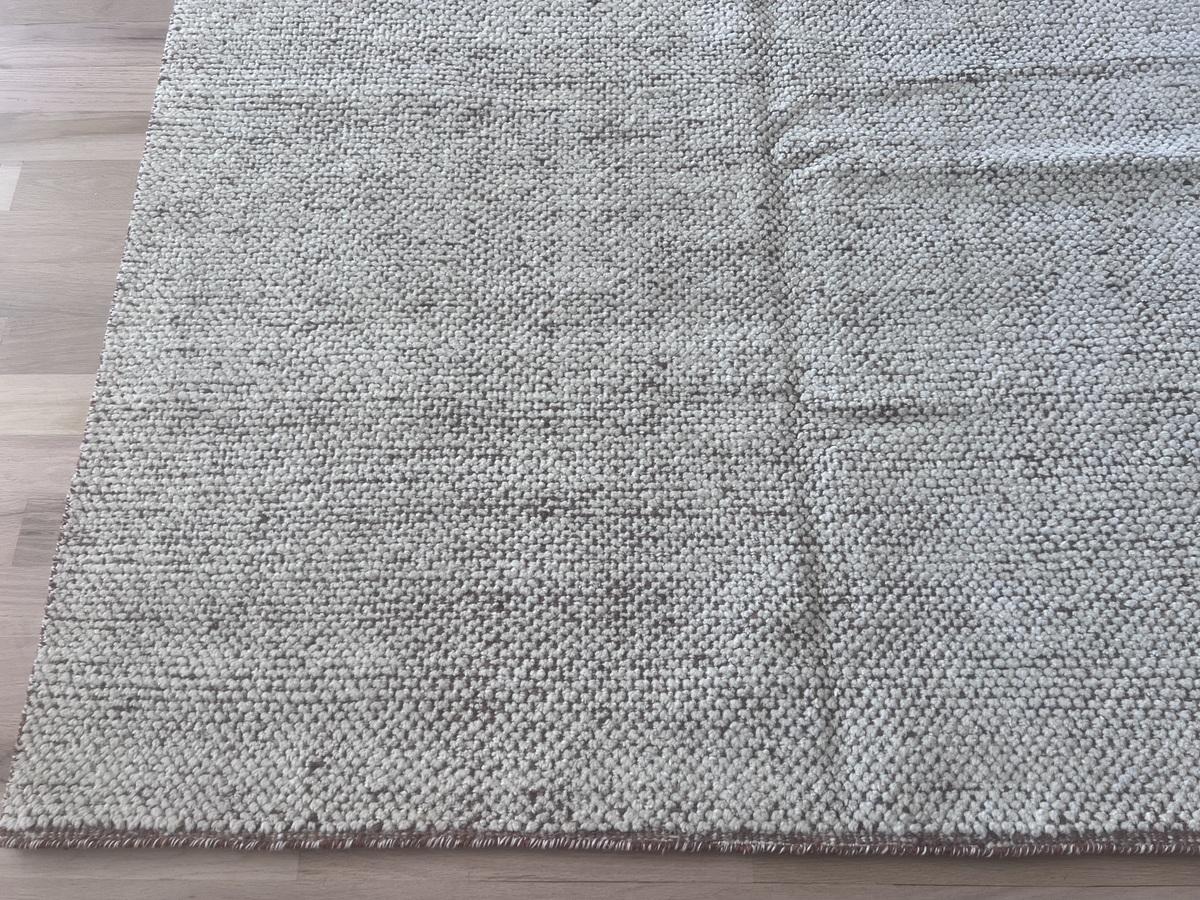 Dieser Teppich mit Kieselsteinmuster in Elfenbein auf Kamel stammt aus unserer neuesten Kollektion marokkanischer Designs und wurde in Indien handgefertigt und handgeknüpft. Das hohe, niedrige Knotenmuster ist ein einfaches, aber strukturiertes