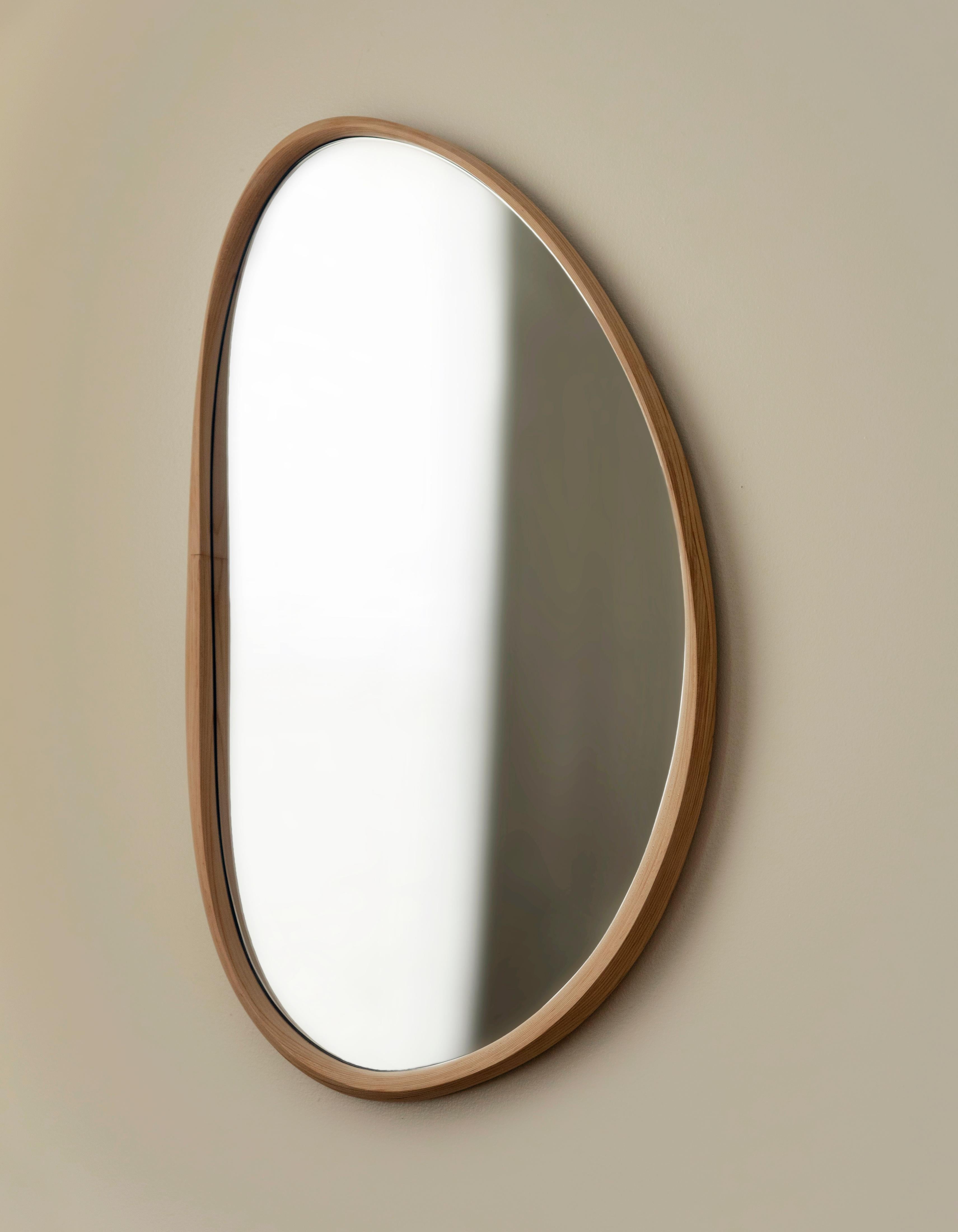 Pebble mirror uses the traditional woodworking technique of bent-lamination to preserve the beauty of twisted wood and preserve tension into a solid object. The undulating thin and thick frame is delicately hand-carved by the artist from fifty