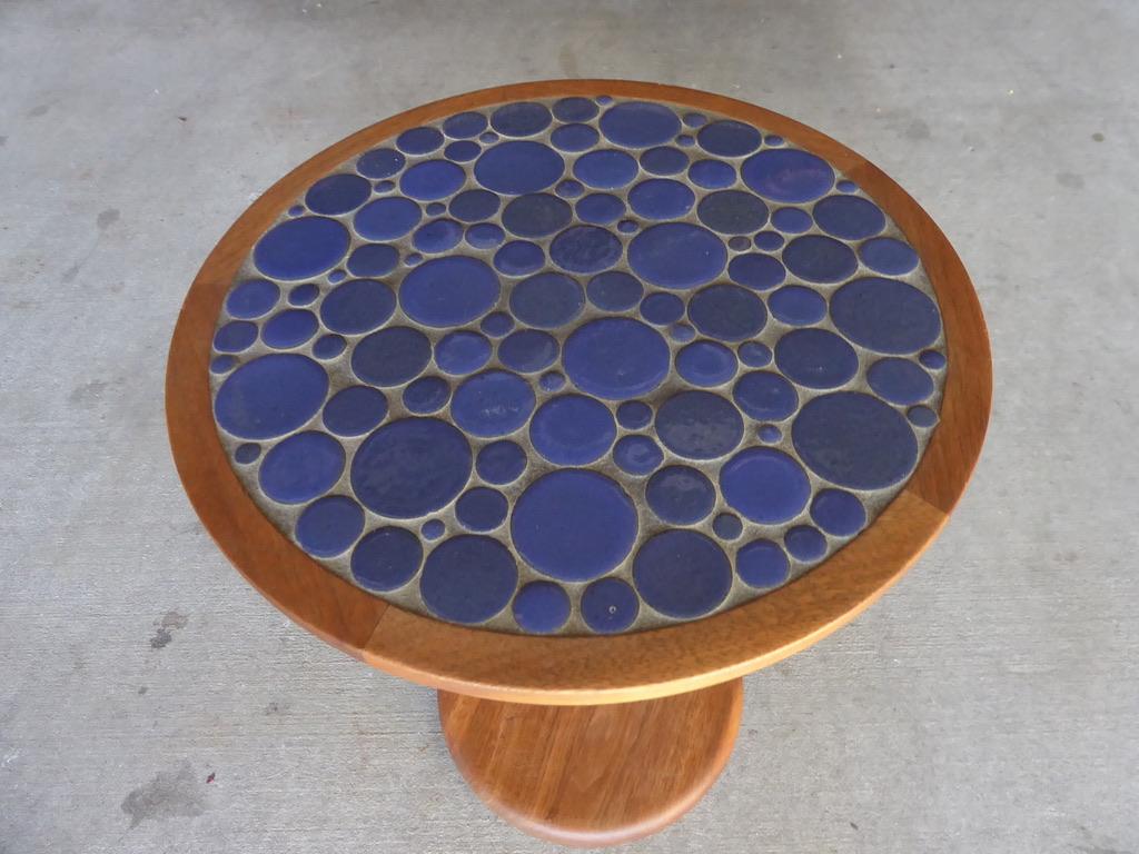 A walnut occasional table with varied sizes of round glazed ceramic tiles set into the top. Designed by Gordon Martz for his firm Marshall Studios in the 1950s. The round mosaic pattern was given the title Pebble Table as a result. Then bottom is