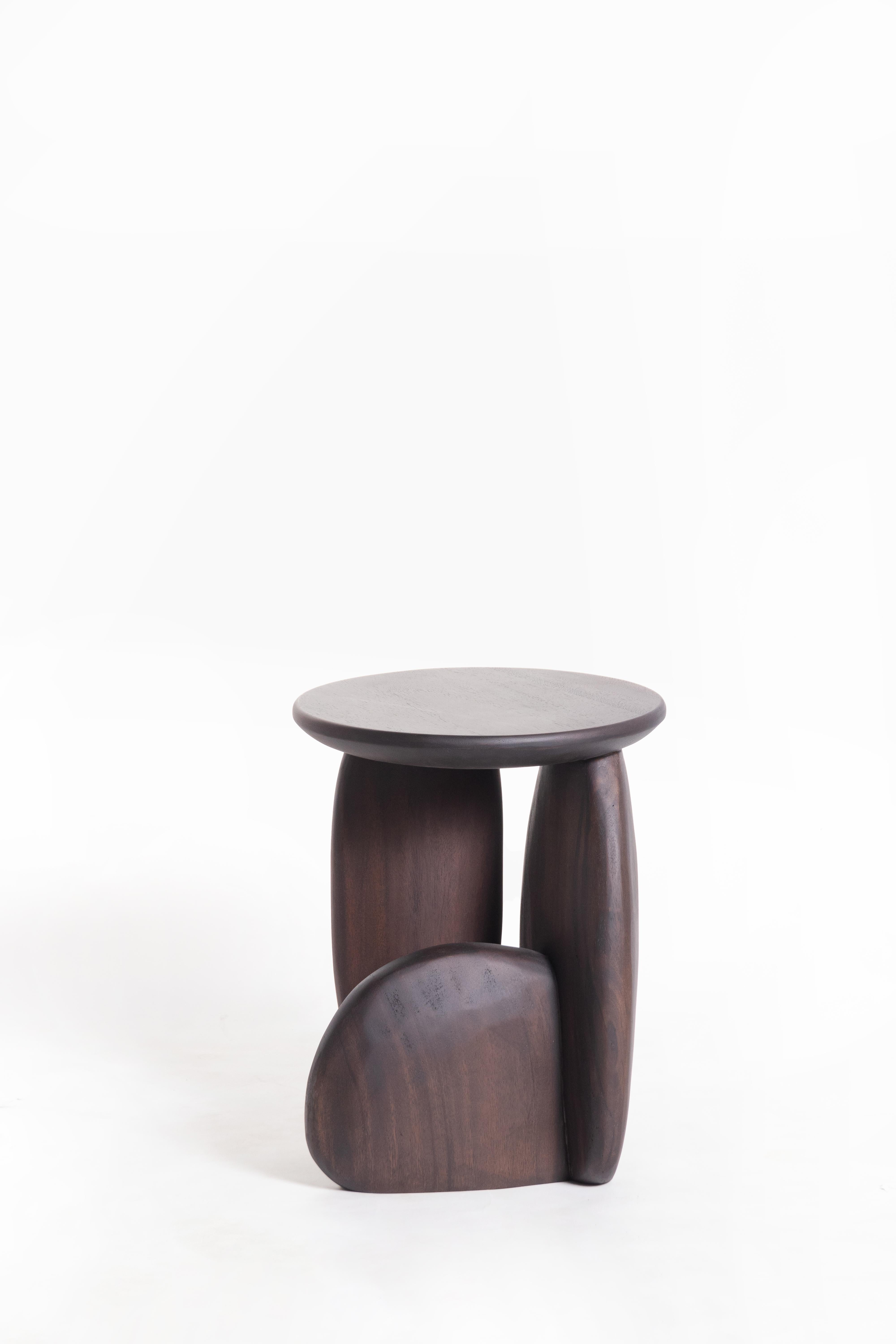 A three-legged wooden stool that looks like the arrangement of rock to form a structure. This work was born from the skill and instinct of a master craftsman where designers give the artisan a chance to create works without a clear plan until