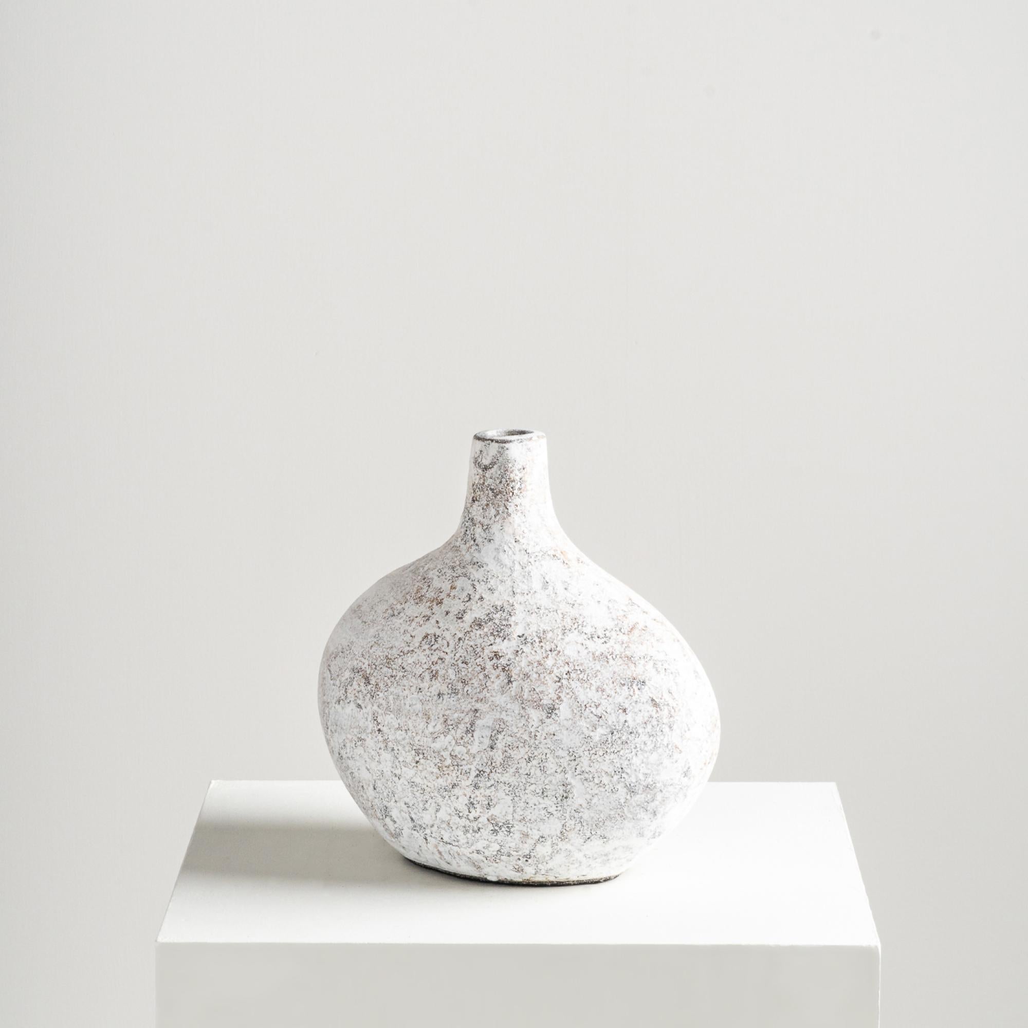Il vaso Pebble, con la sua forma unica a bulbo appiattito e i suoi dettagli strutturati, valorizza qualsiasi ambiente. Realizzato a mano con argilla di terracotta, la sua finitura naturale e le sue texture rustiche infondono un'essenza giocosa ma