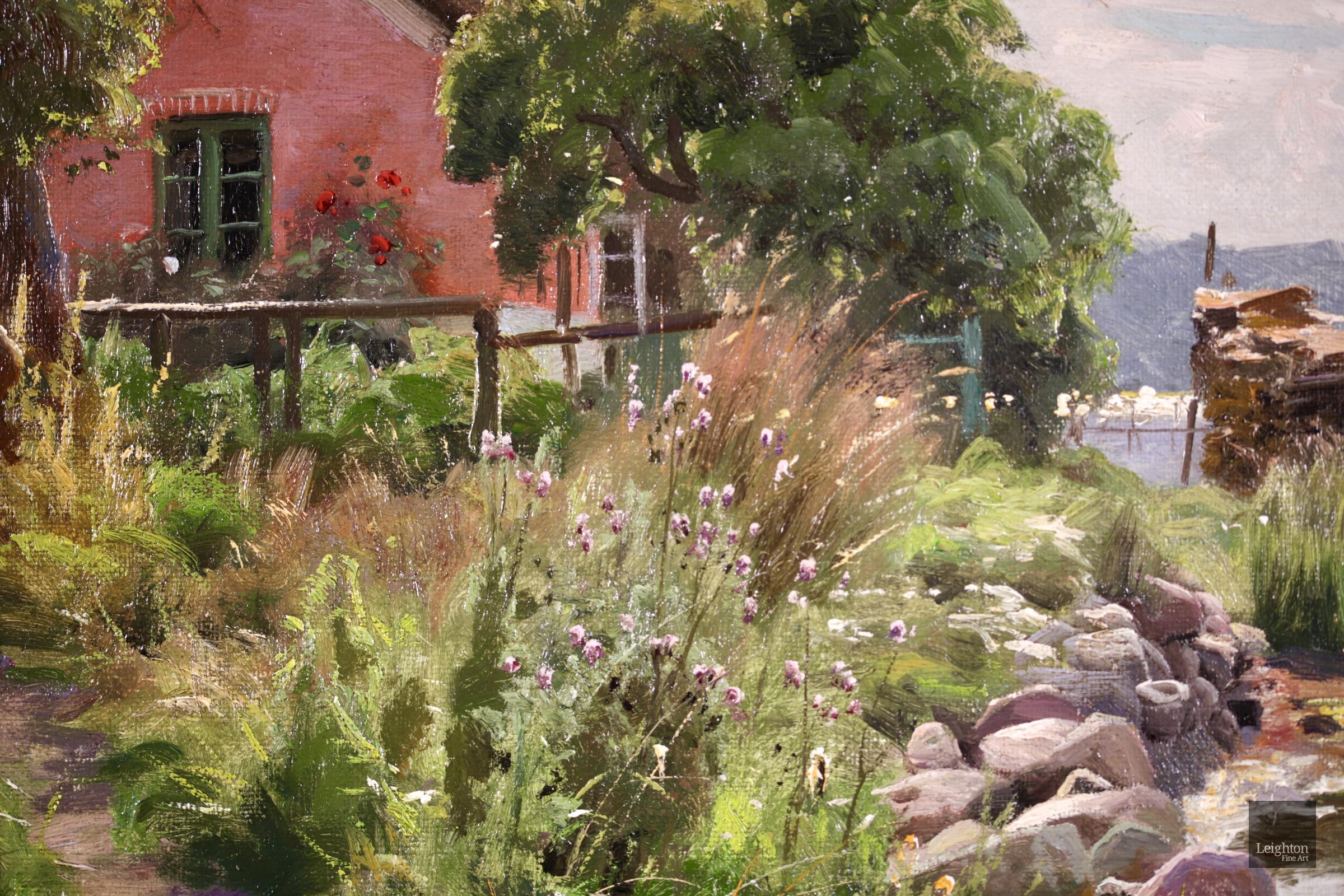 Eine charmante Flusslandschaft in Öl auf Leinwand des dänischen Realisten Peder Mork Monsted. Das Gemälde zeigt eine schöne Frühlingslandschaft an einem strahlenden Tag. Ein Mann steht am Ufer eines Flusses vor einem rosafarbenen Häuschen und