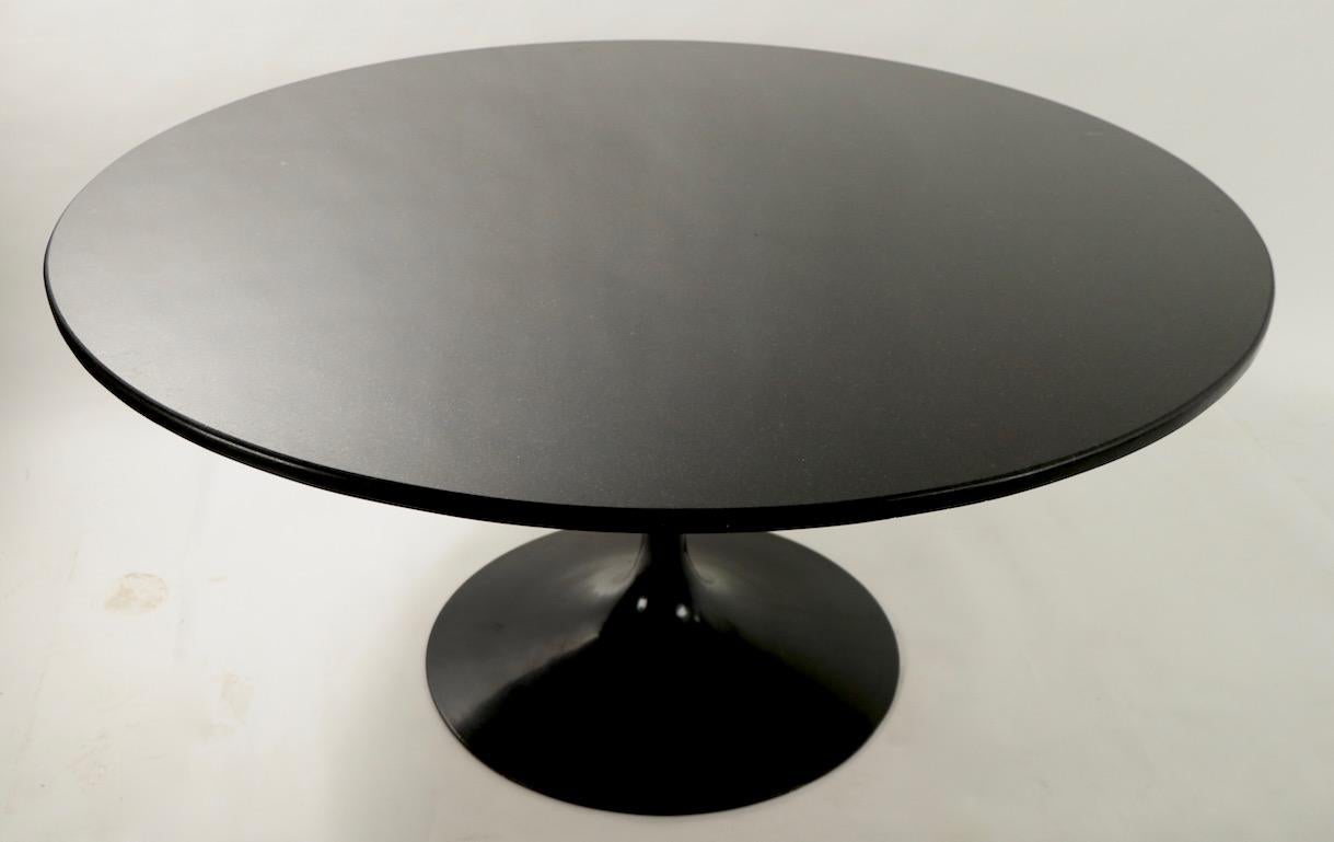 Stunning black on black modernist style dining table having a polished granite top and cast metal hourglass form pedestal base, after Saarinen. Substantial table, clean ready to use condition. Measures: Diameter of Top 54 x diameter of base 26 x