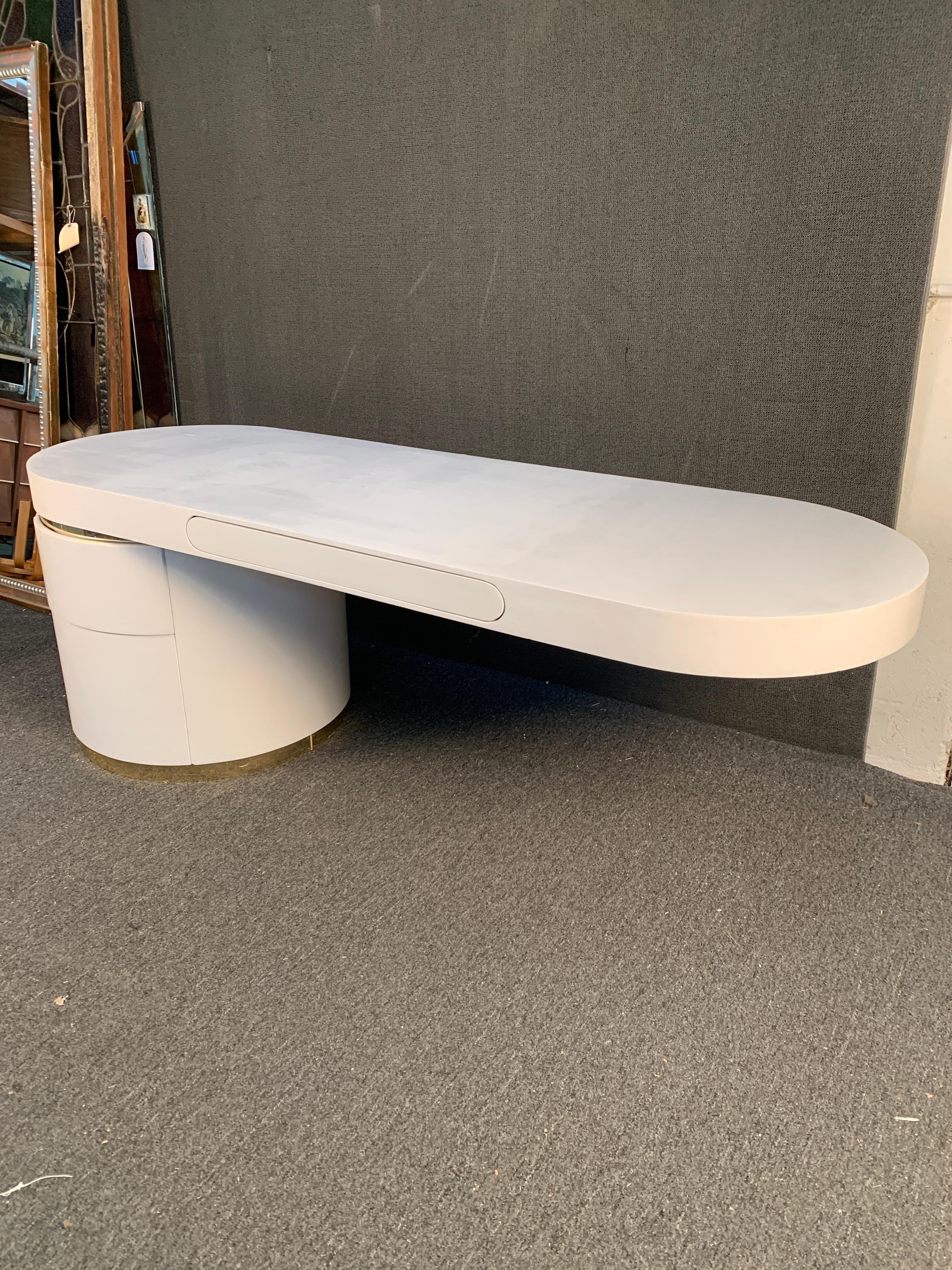 This unique contemporary modern pedestal desk features stunning cantilever design with three spacious drawers for storage. Unique goatskin style finish is accented by brass colored metal trim. Simple clean lines add to the futuristic appeal of this