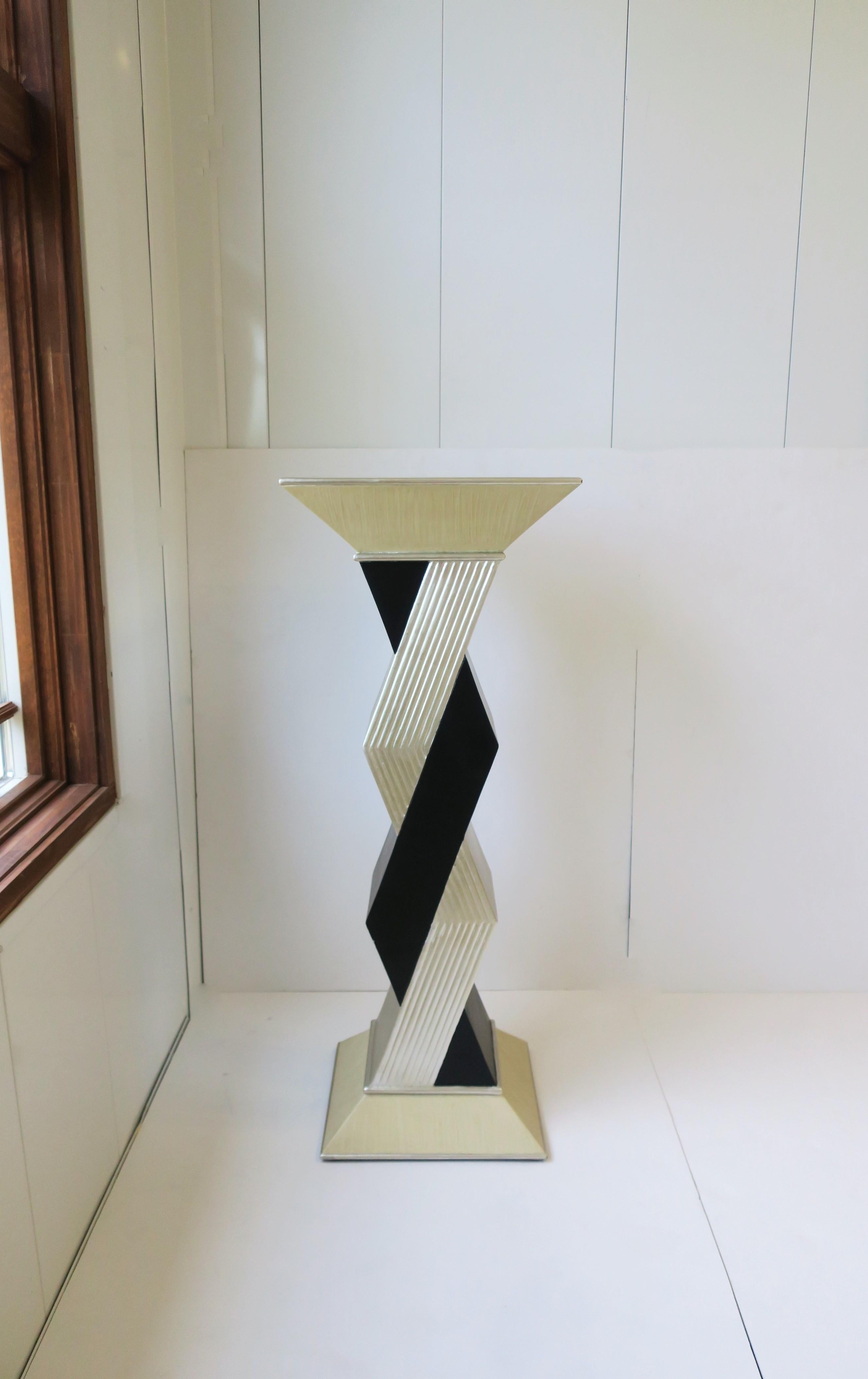 A Postmodern style pedestal column pillar stand in matte black and silver-gilt style zig-zag design, late 20th century, circa 1990s. Top and base area are a light tan hue finished with a silver edge. A great piece for sculpture, plant, display of