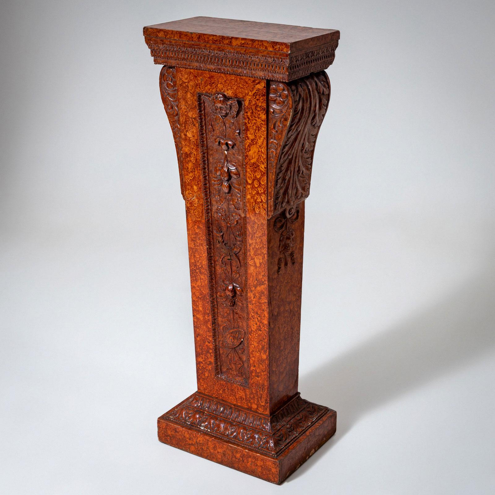 Pedestal o columna redonda con una base alta y lisa, un fuste acanalado y recto con una base más pequeña. La columna está chapada en caoba e incrustada con dos hilos de una madera clara en el tercio inferior y decorada con una banda incrustada en